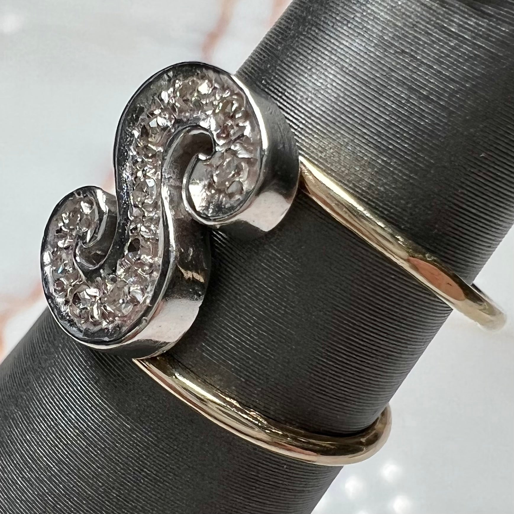 A two tone white and yellow gold initial ring of the letter "S" set with diamonds.