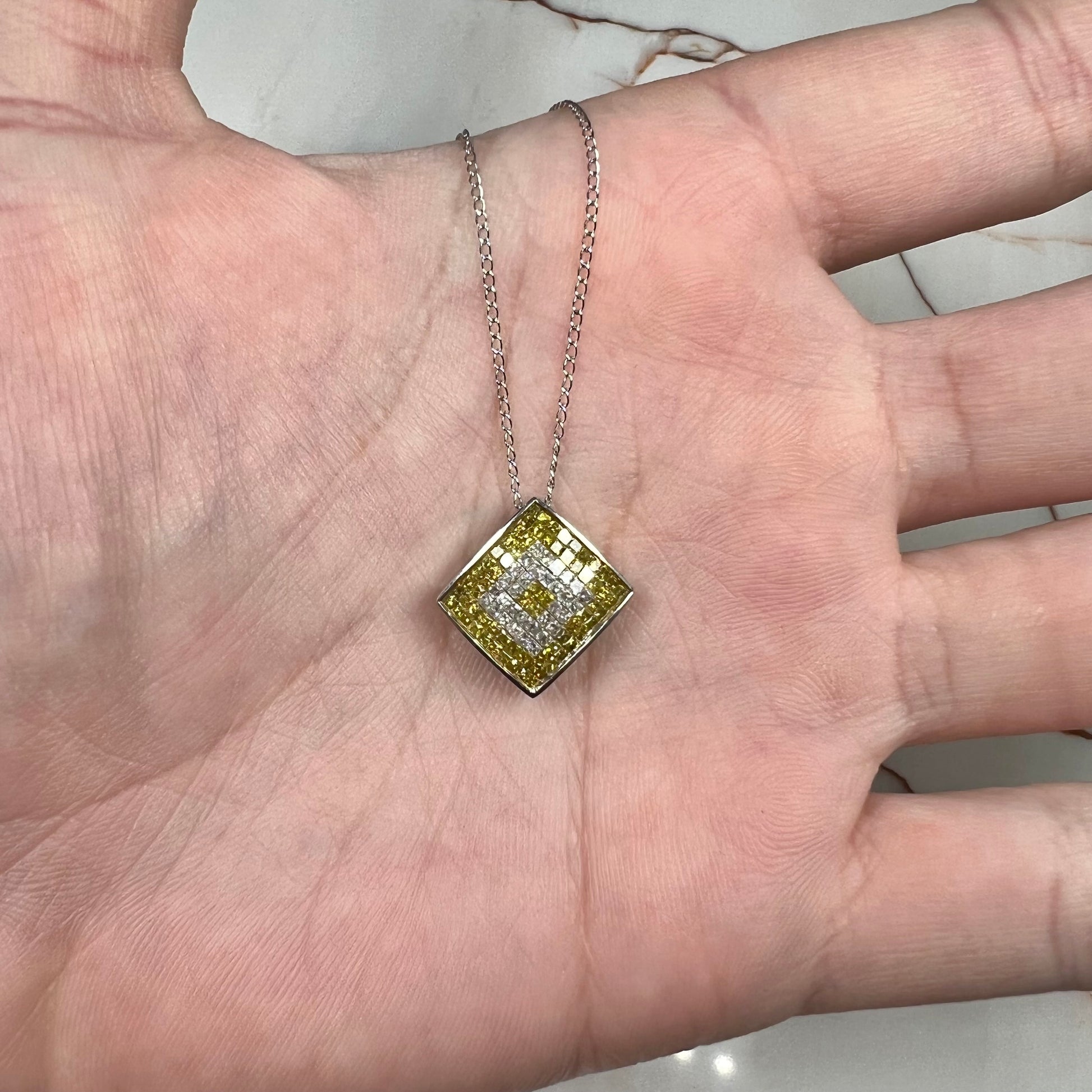A square shaped necklace set with princess cut yellow and white diamonds in a white gold setting on a white gold chain.