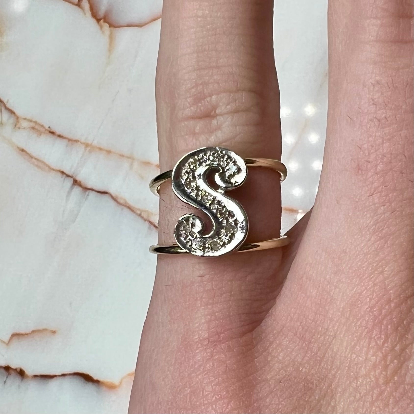 A two tone white and yellow gold initial ring of the letter "S" set with diamonds.