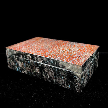 A custom stone box handmade by Gems Art Studio from polished red dinosaur bone and blue pietersite.