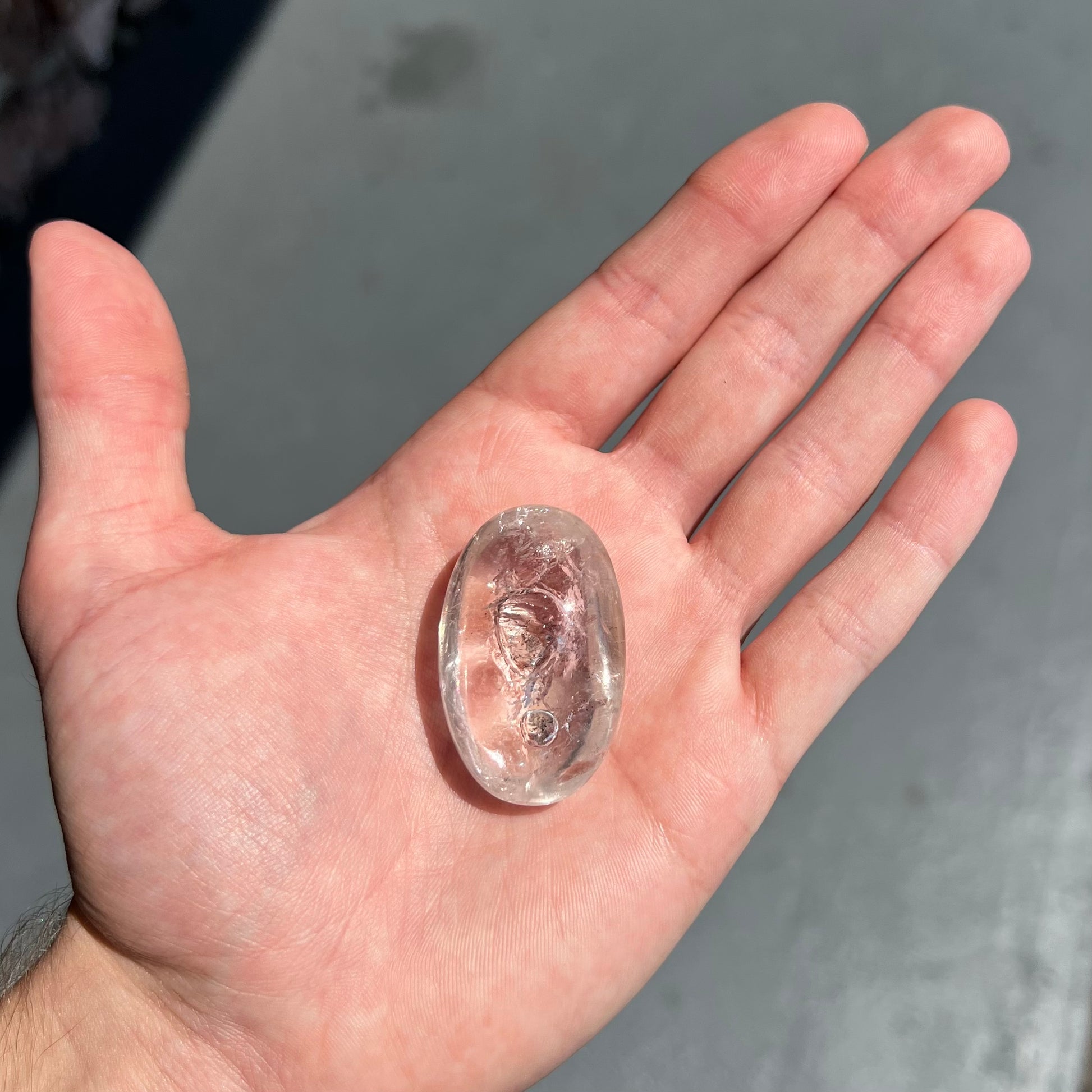 A polished clear quartz with two liquid enhydro inclusions around a solid phantom crystal inclusion.