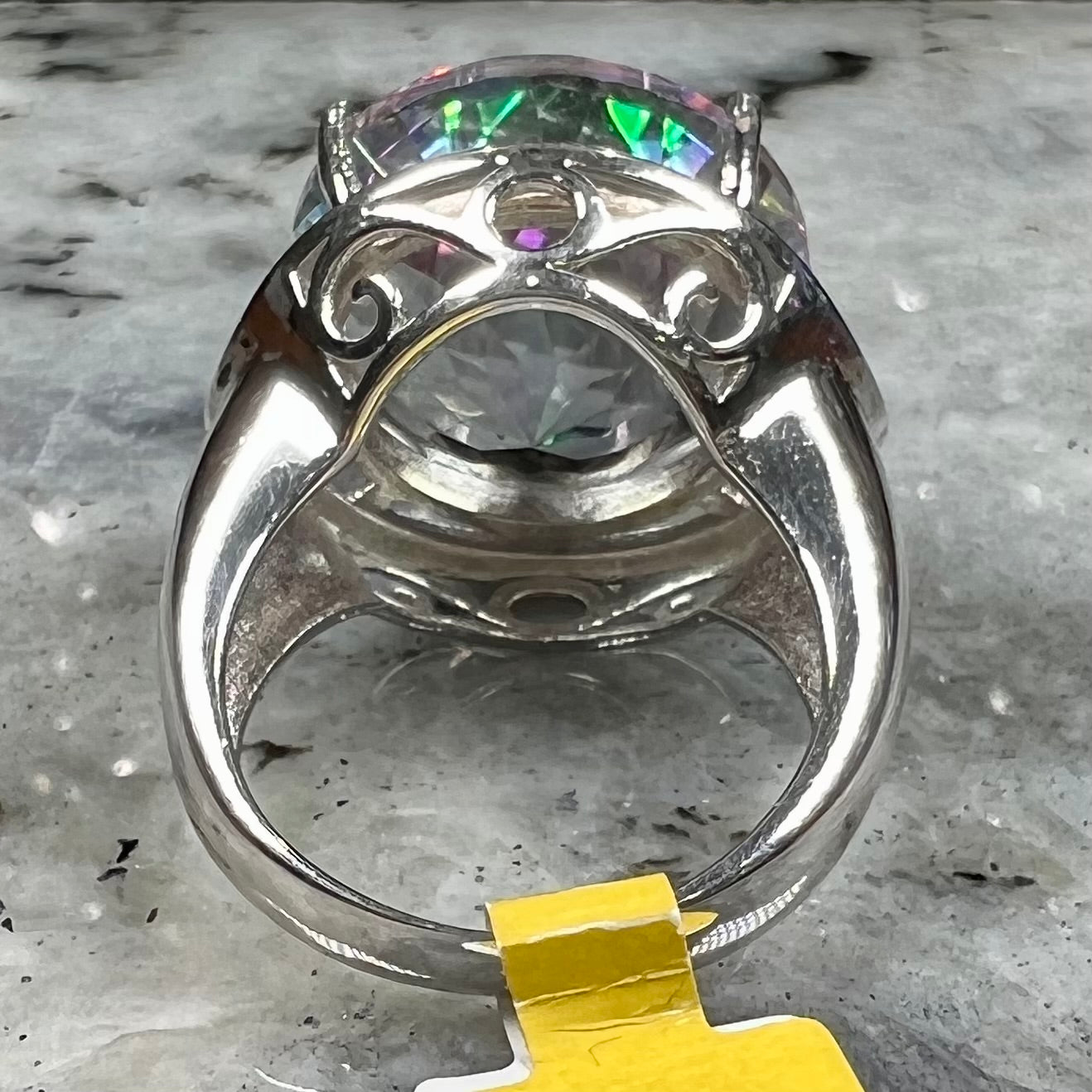 A large, round cut pink and green mystic topaz set in a sterling silver ring with white topaz accent stones.