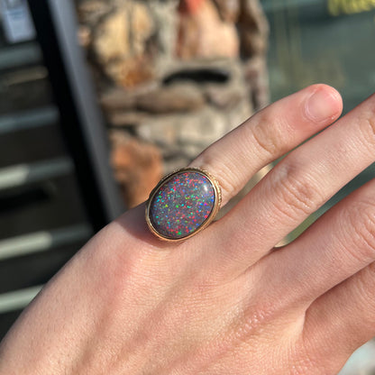 A bright black Andamooka opal that displays a pinfire pattern set in a vintage-style yellow gold bezel ring.