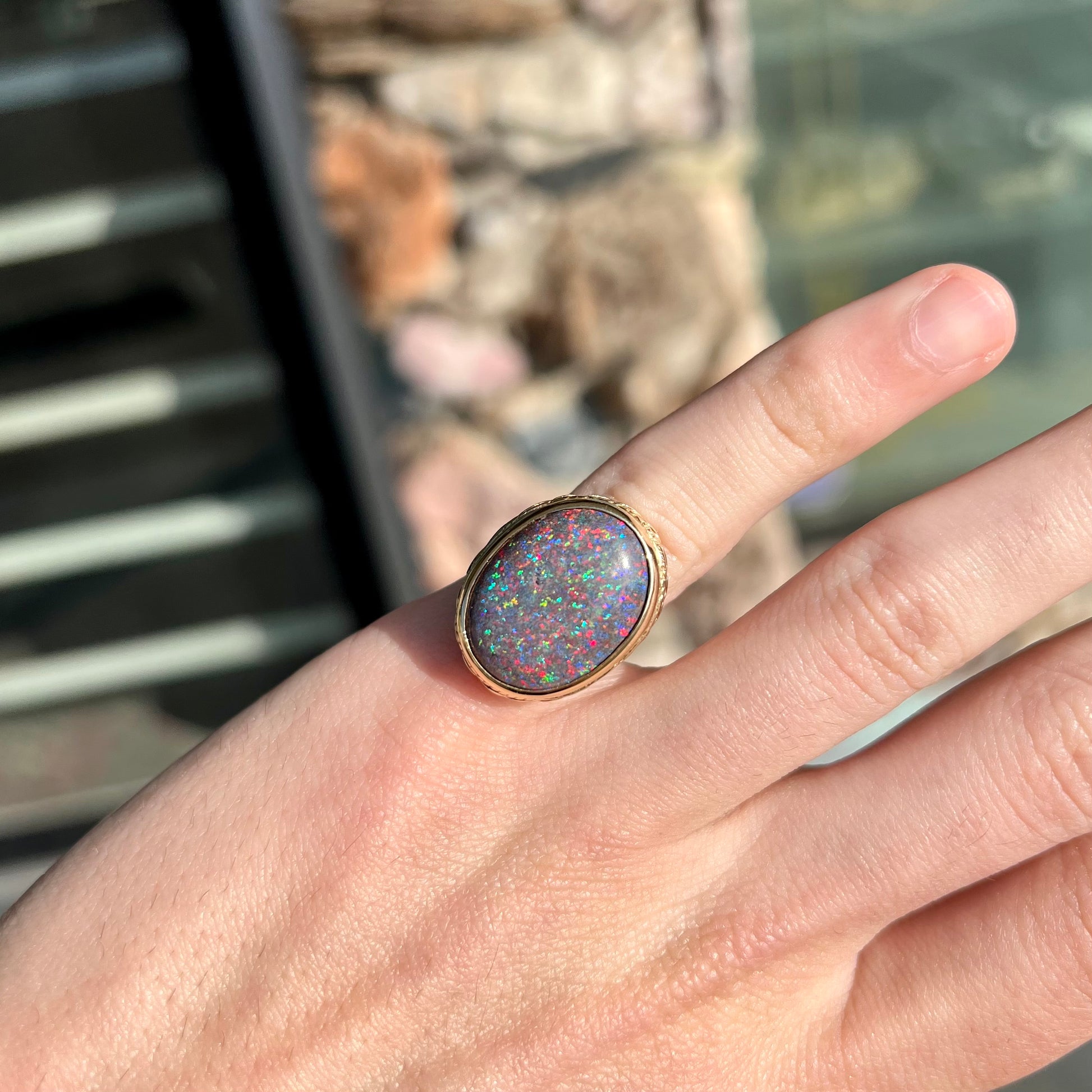 A bright black Andamooka opal that displays a pinfire pattern set in a vintage-style yellow gold bezel ring.