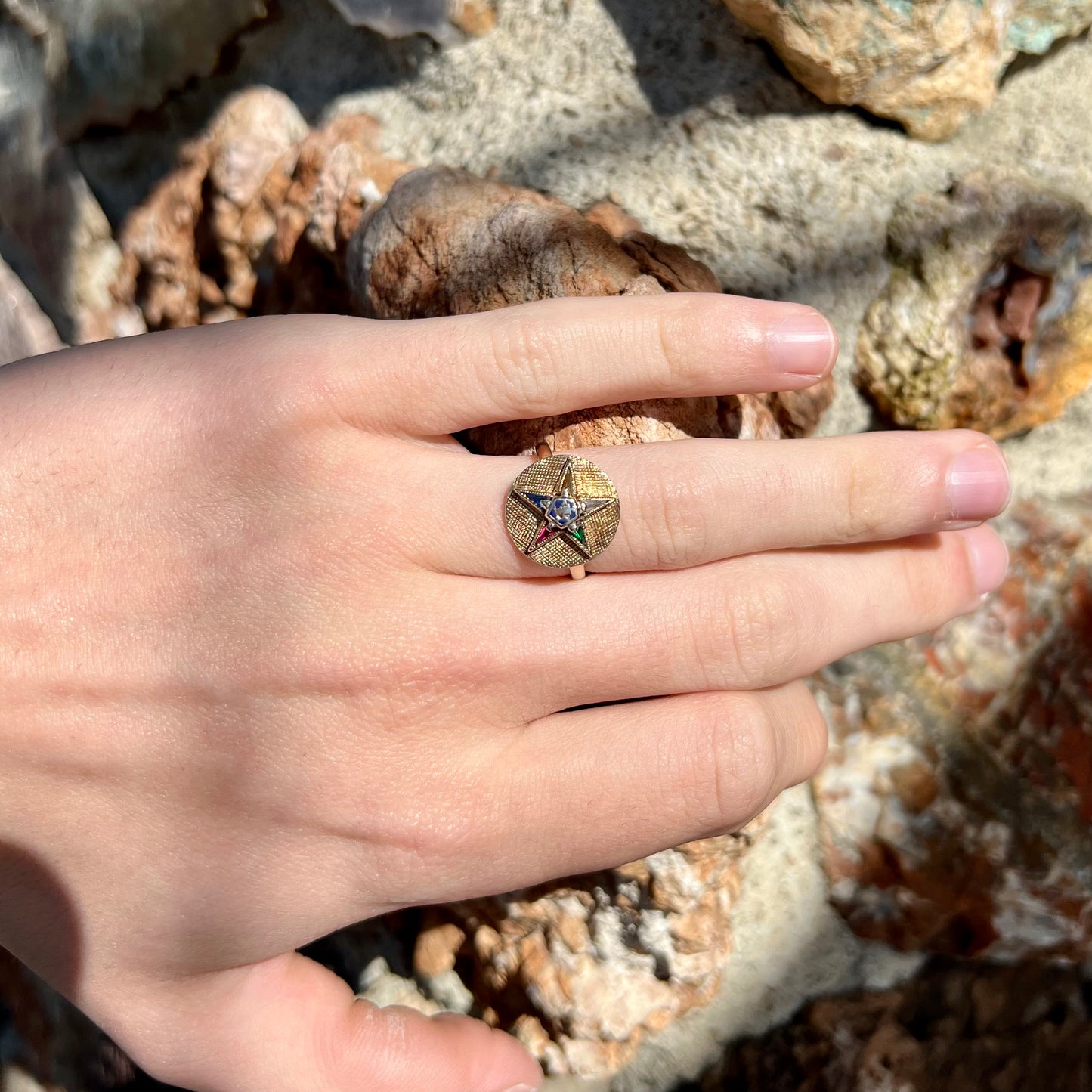 A gold ring set with multicolored synthetic sapphires forming a star with a blue enameled center, symbolizing the Order of the Eastern Star.