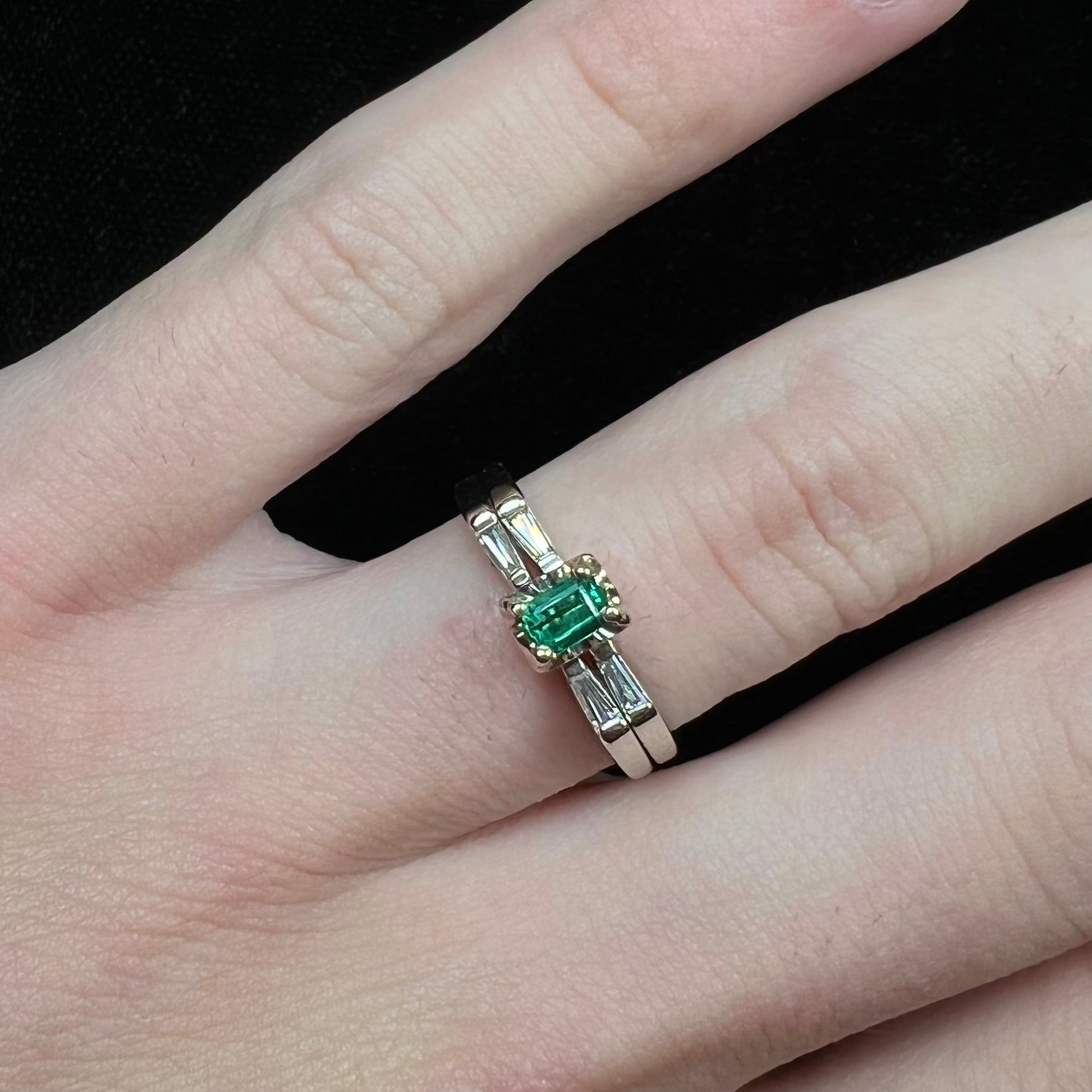 A white gold emerald and baguette cut diamond engagement and wedding set.