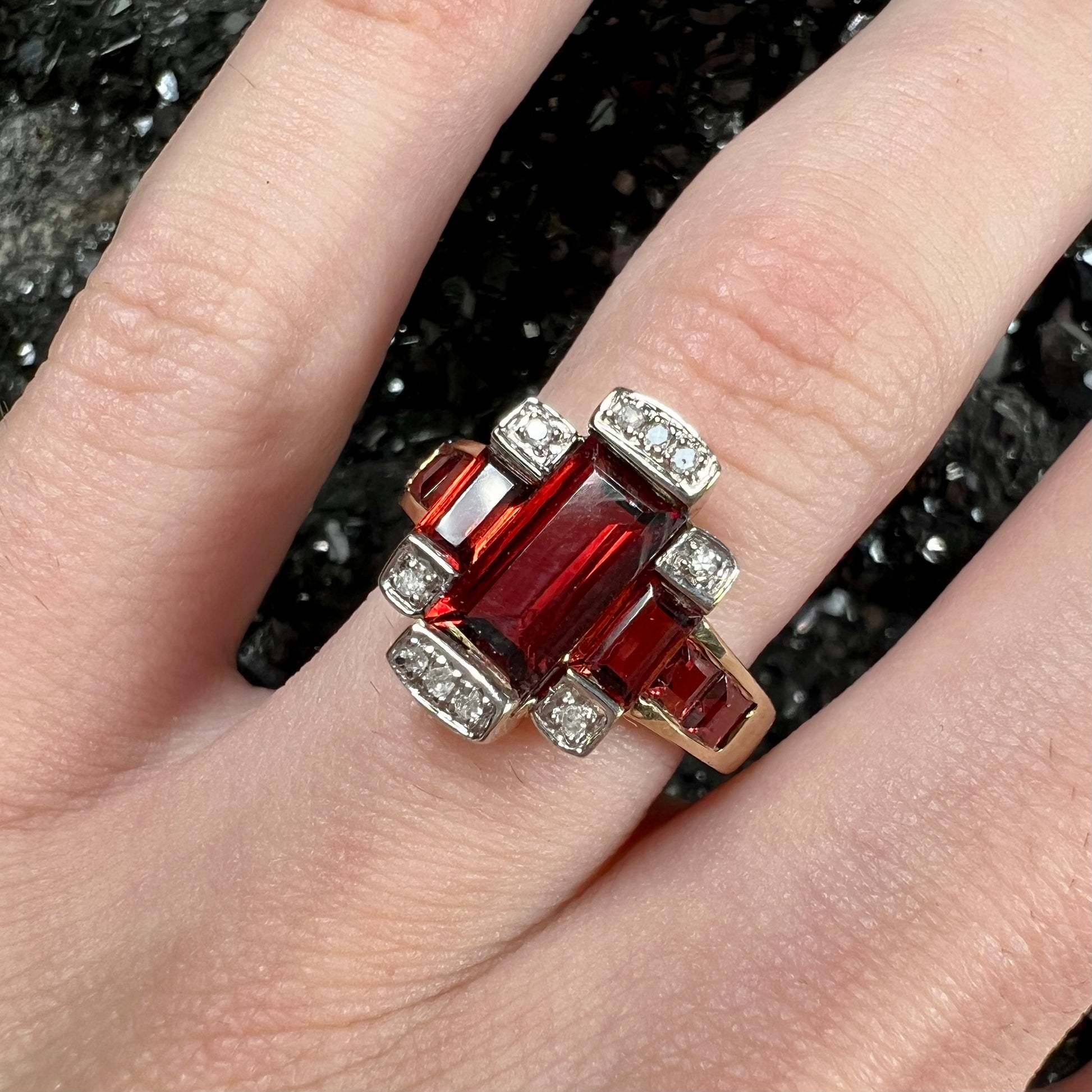 An Art Deco style emerald cut garnet and diamond ring cast in yellow gold.