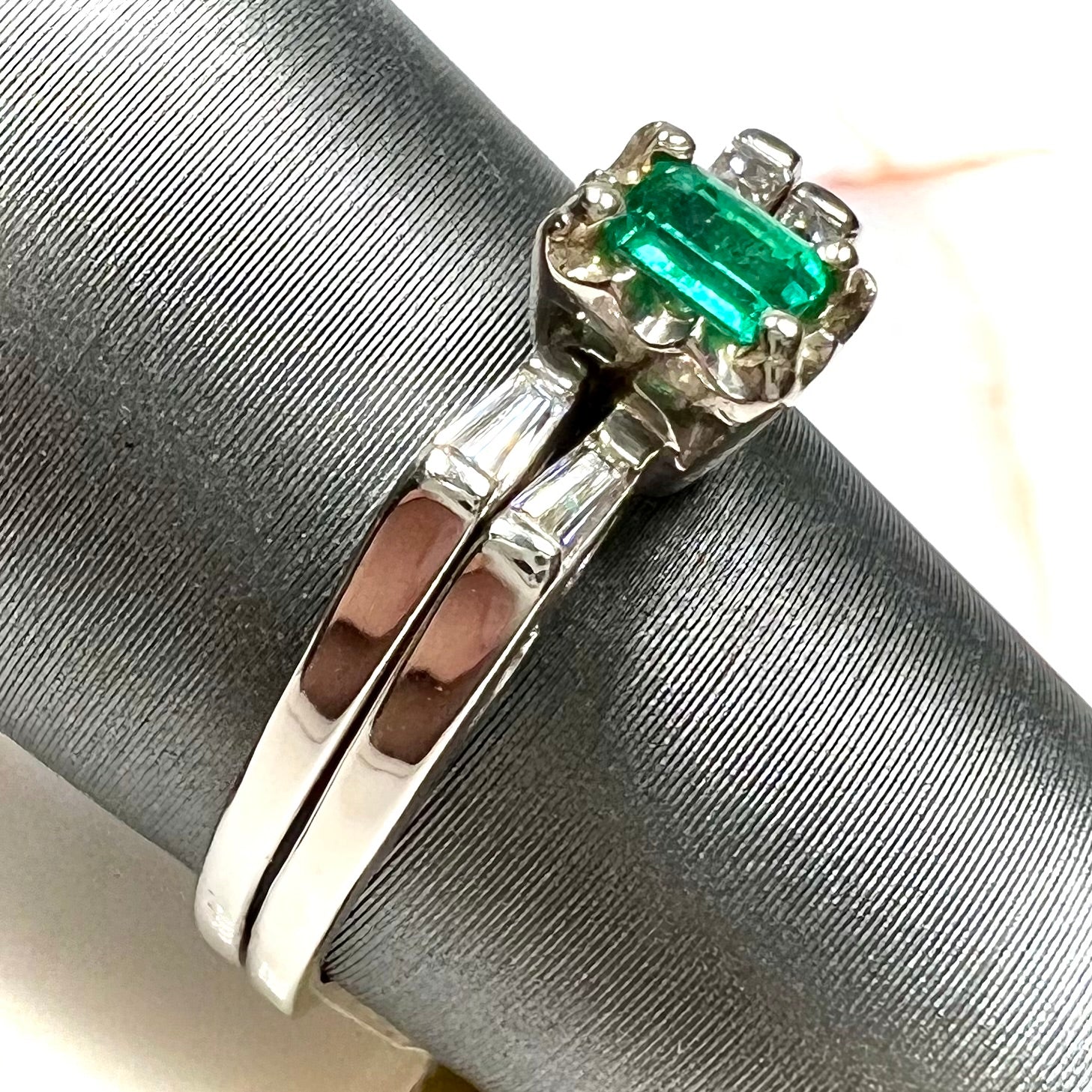 A white gold emerald and baguette cut diamond engagement and wedding set.
