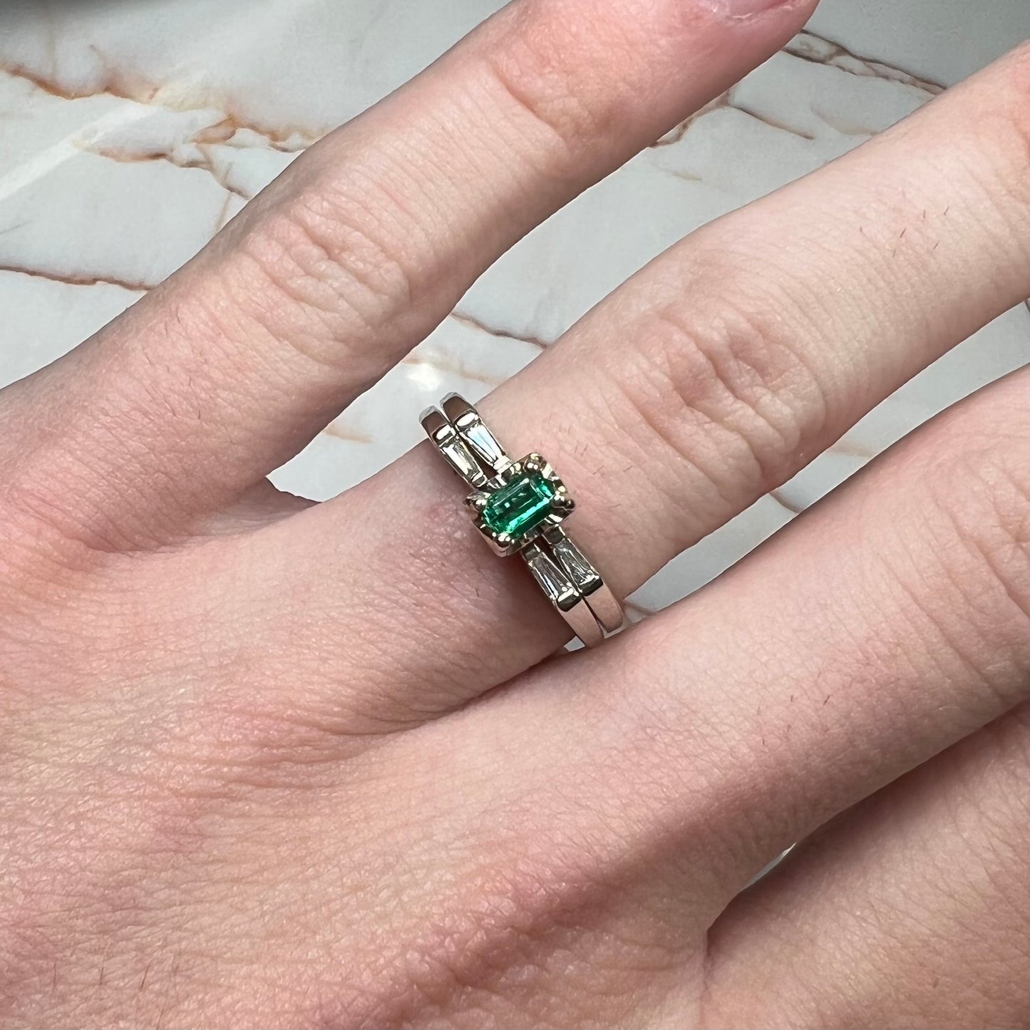 A white gold emerald and baguette cut diamond engagement and wedding set.