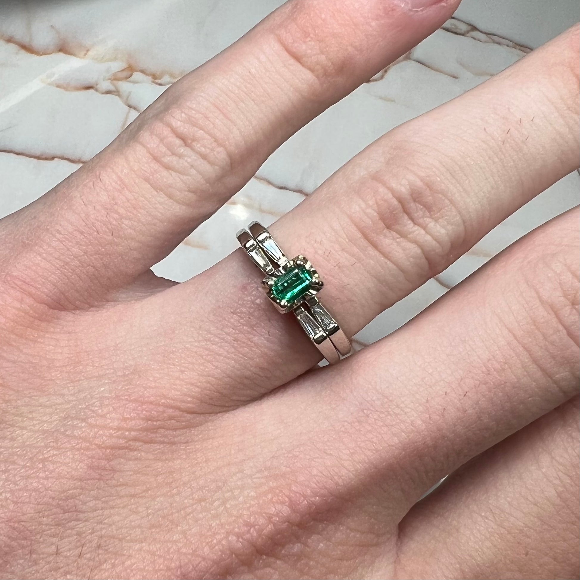 A white gold emerald and baguette cut diamond engagement and wedding set.