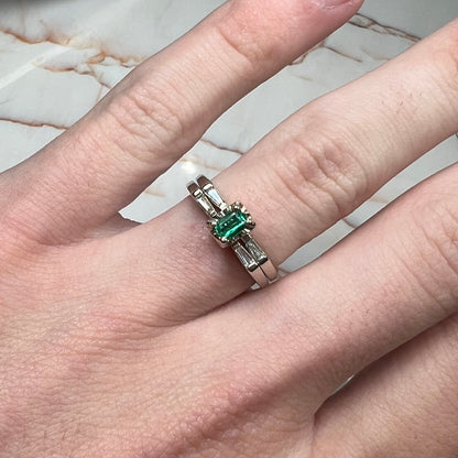 A white gold emerald and baguette cut diamond engagement and wedding set.
