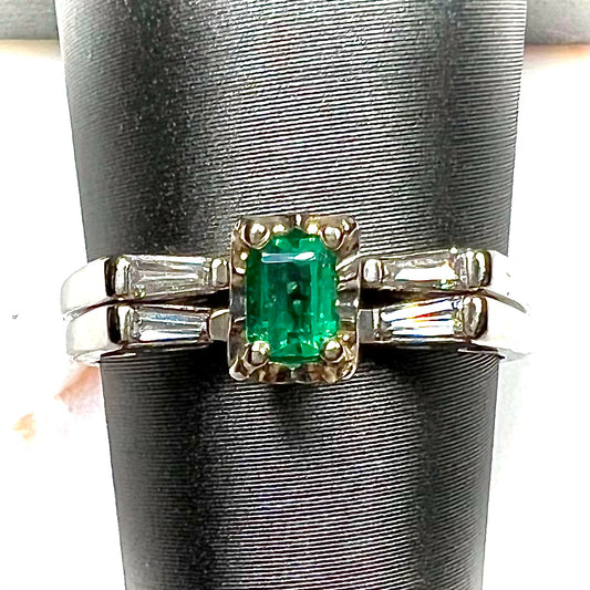 A white gold emerald and baguette cut diamond engagement and wedding set.