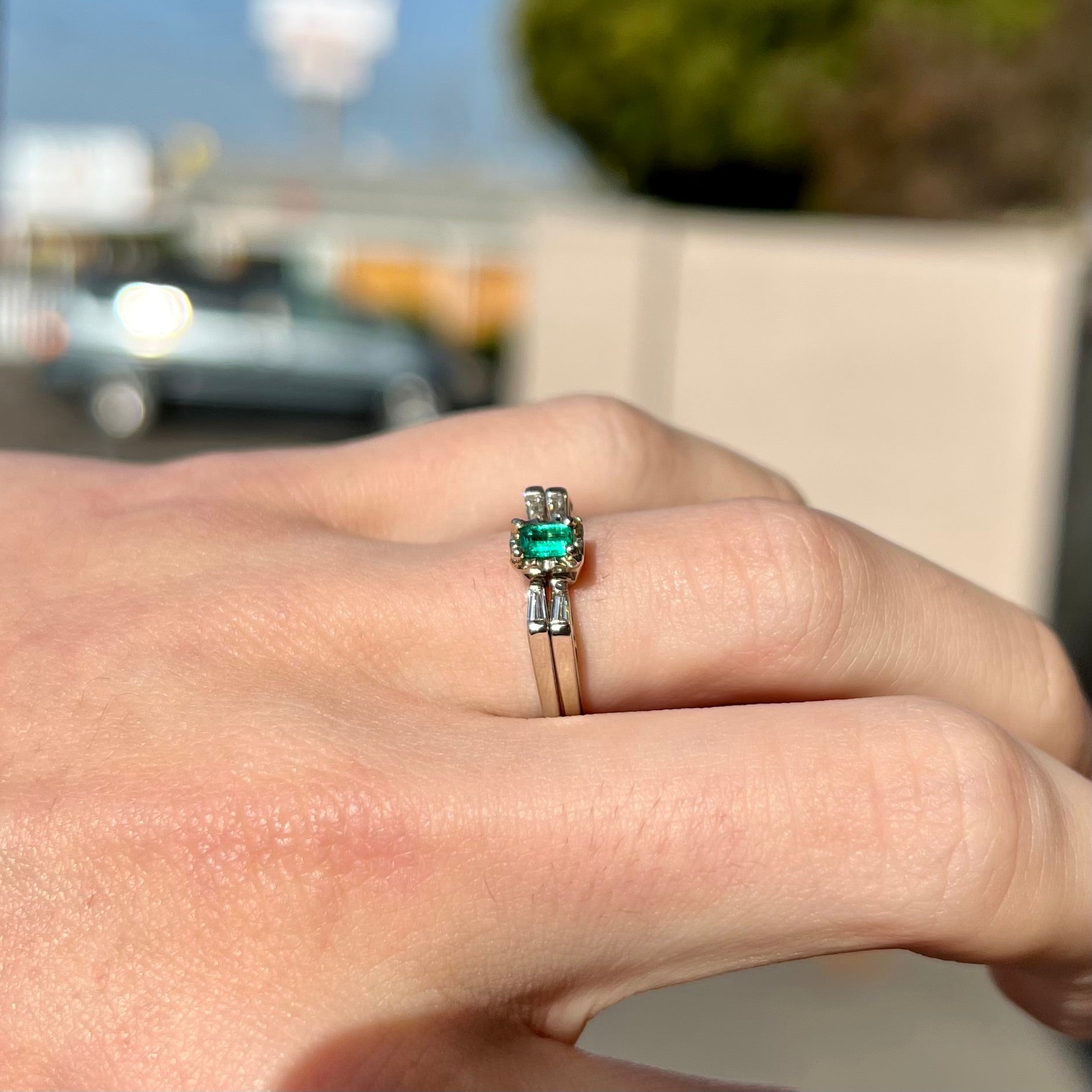 A white gold emerald and baguette cut diamond engagement and wedding set.