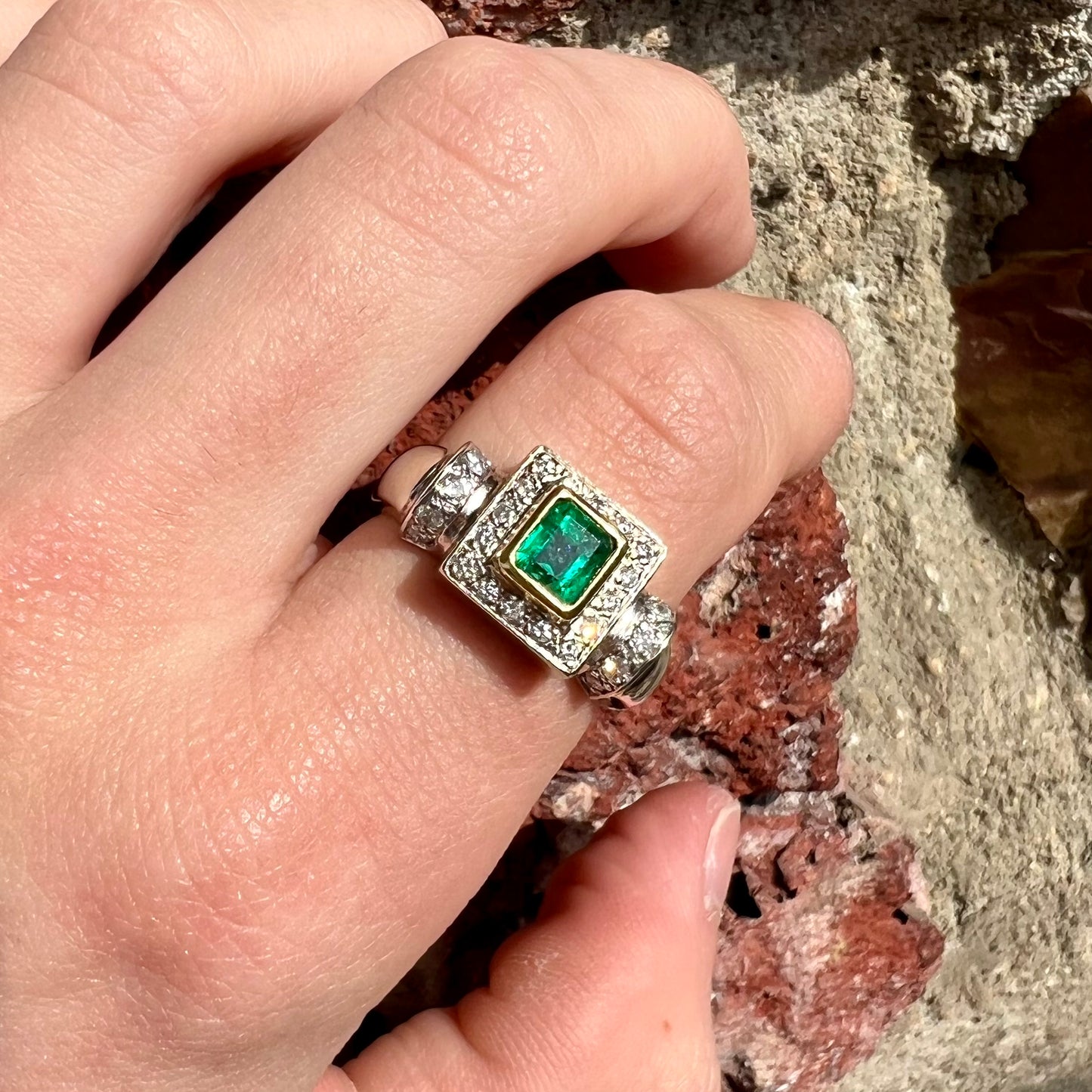 A two tone gold emerald and diamond halo ring.