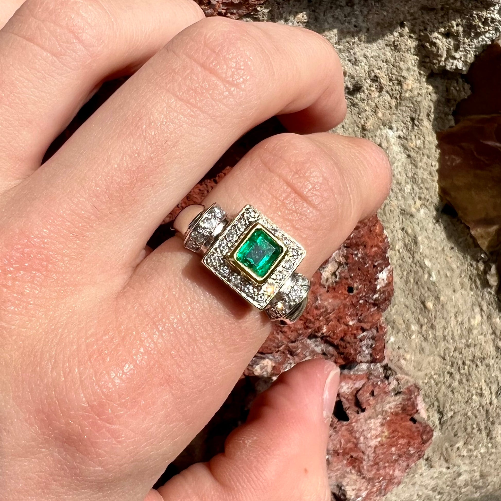A two tone gold emerald and diamond halo ring.