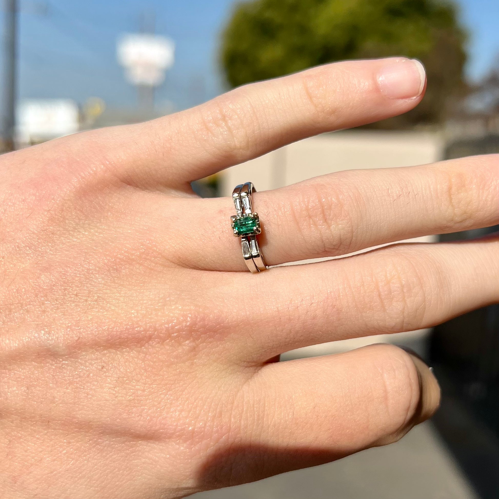 A white gold emerald and baguette cut diamond engagement and wedding set.
