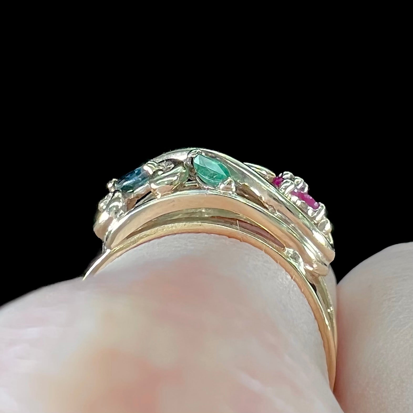 A yellow gold ladies' ring featuring the motif of a flower with leaves set with emeralds, rubies, sapphires, and a  diamond.