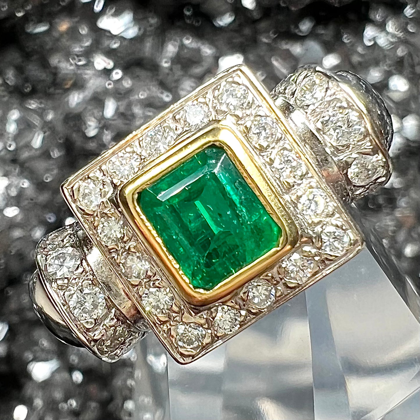 A two tone gold emerald and diamond halo ring.