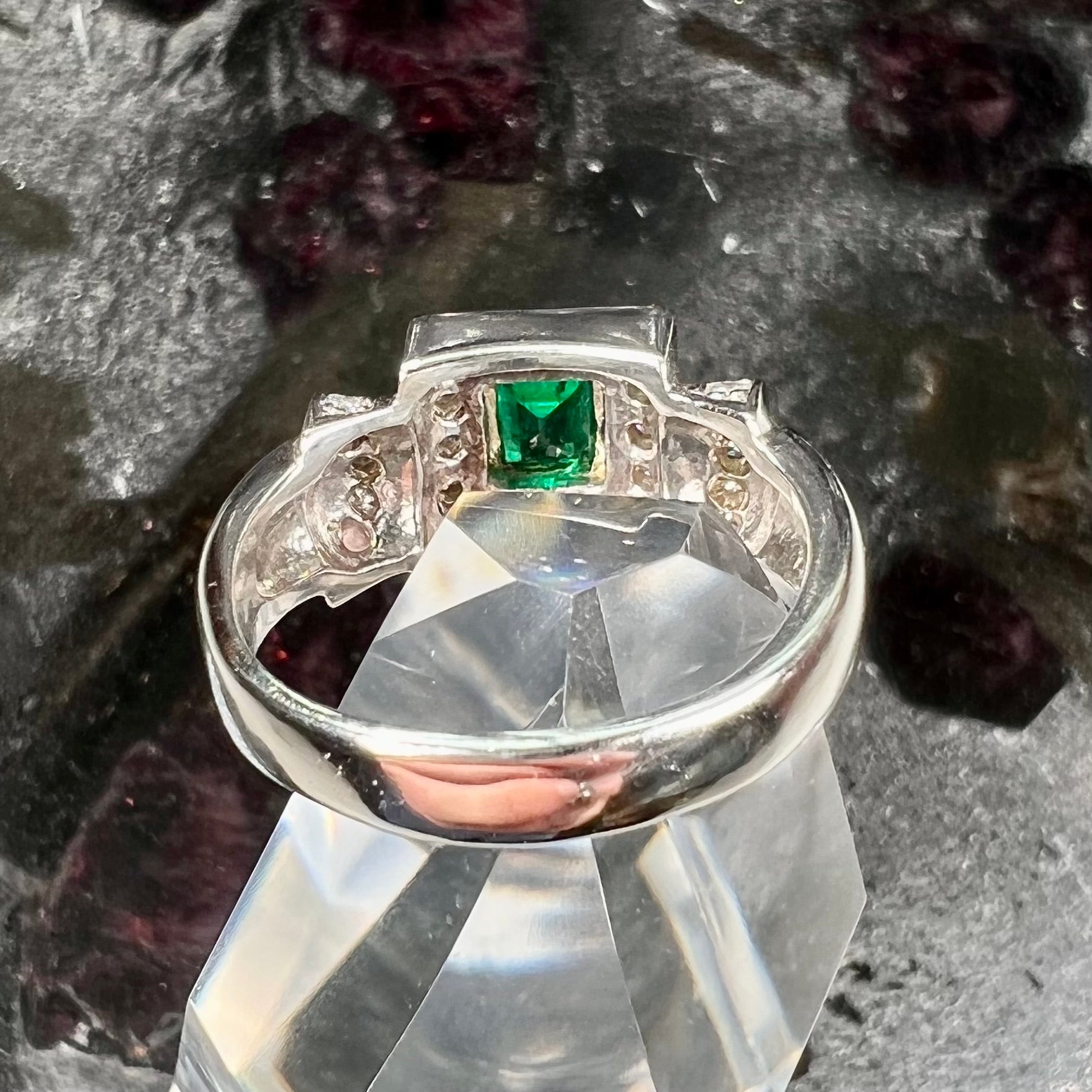 A two tone gold emerald and diamond halo ring.