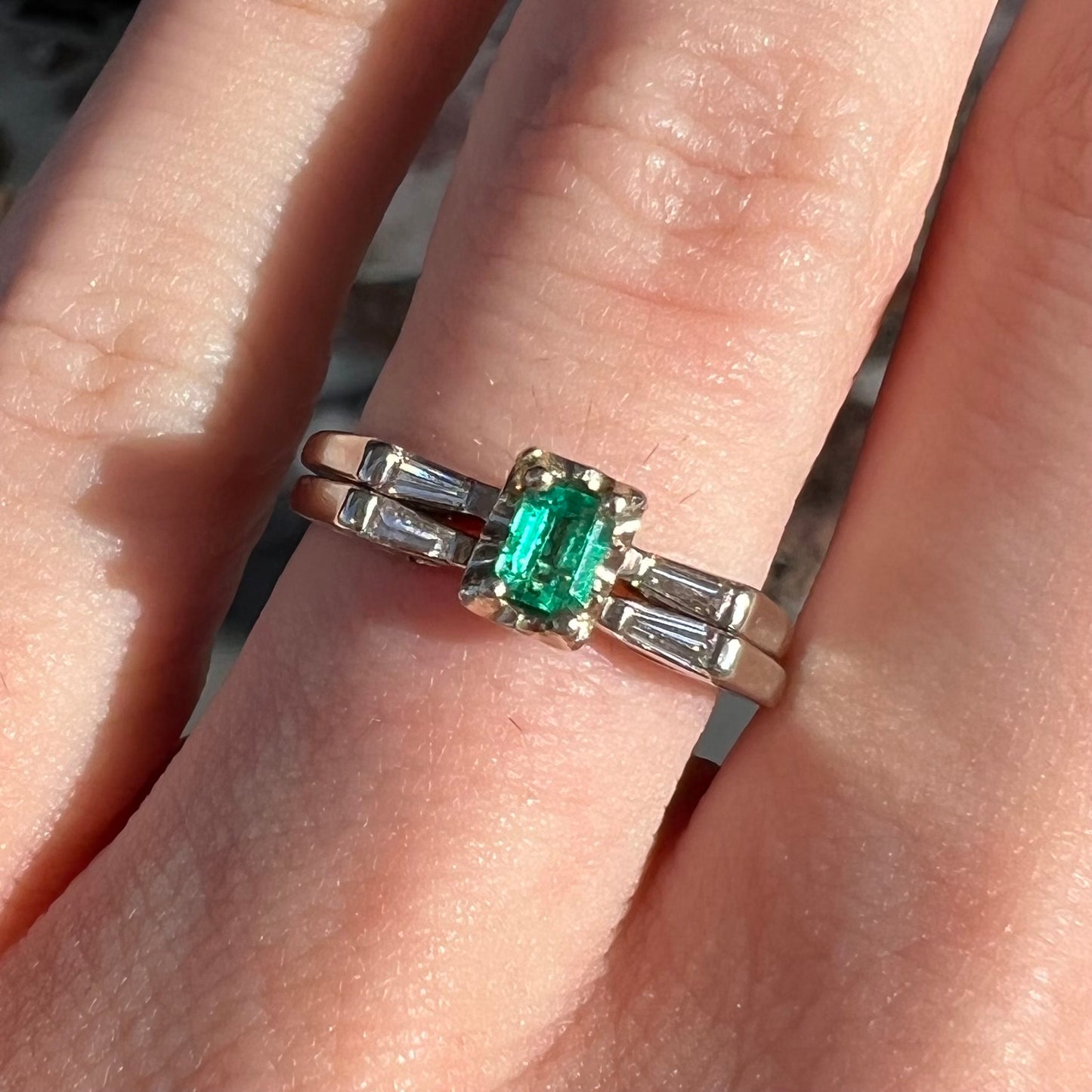 A white gold emerald and baguette cut diamond engagement and wedding set.