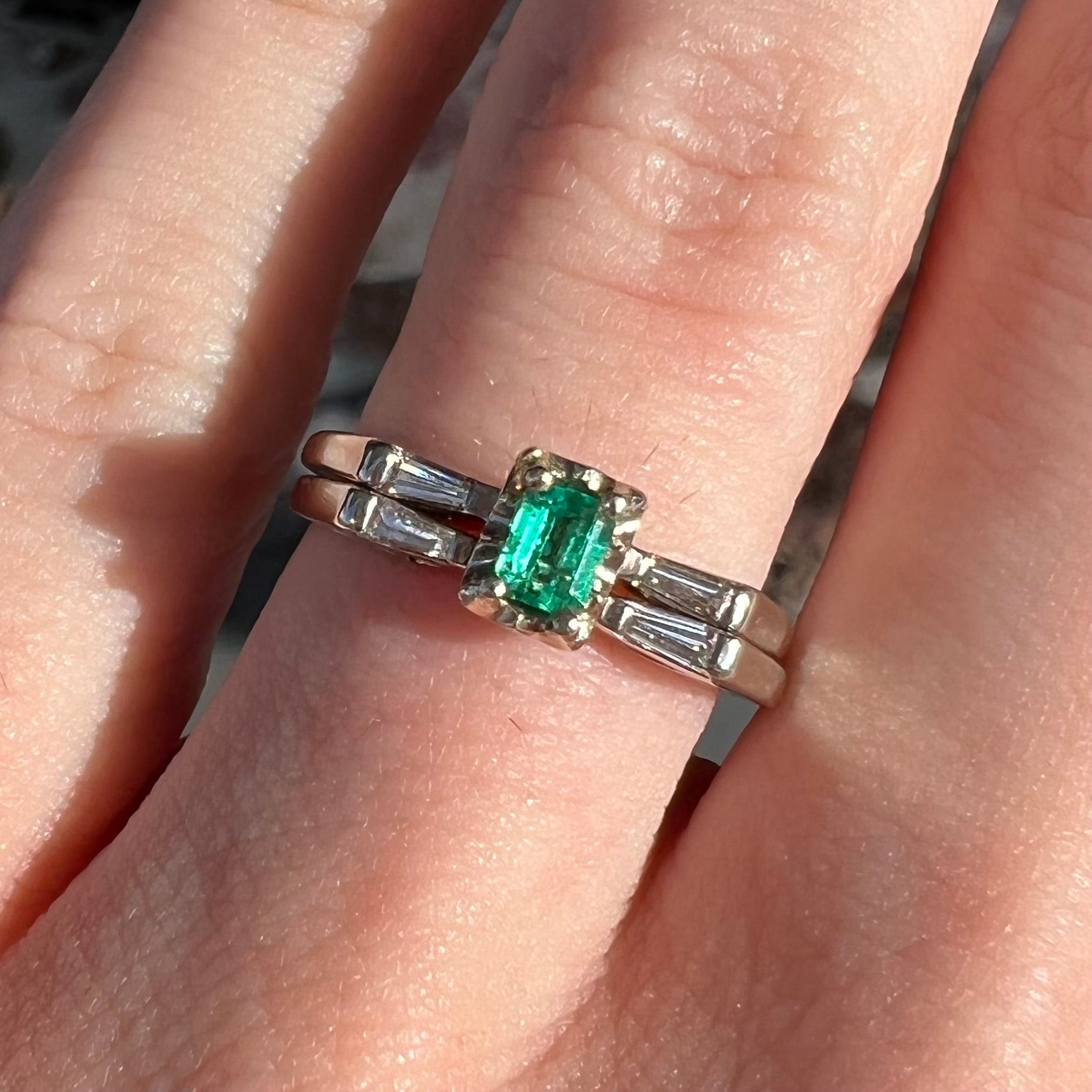 A white gold emerald and baguette cut diamond engagement and wedding set.