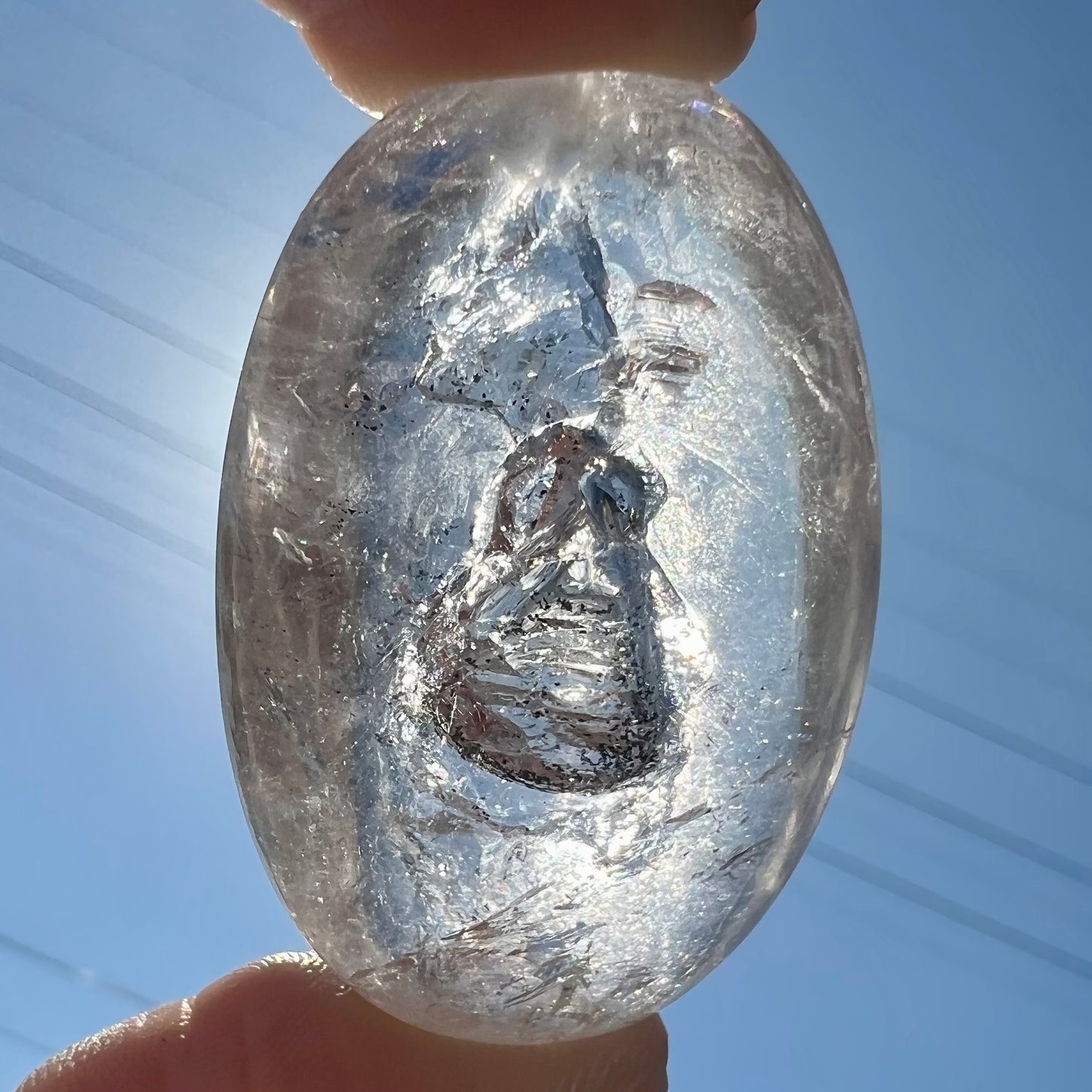 A polished clear quartz with two liquid enhydro inclusions around a solid phantom crystal inclusion.