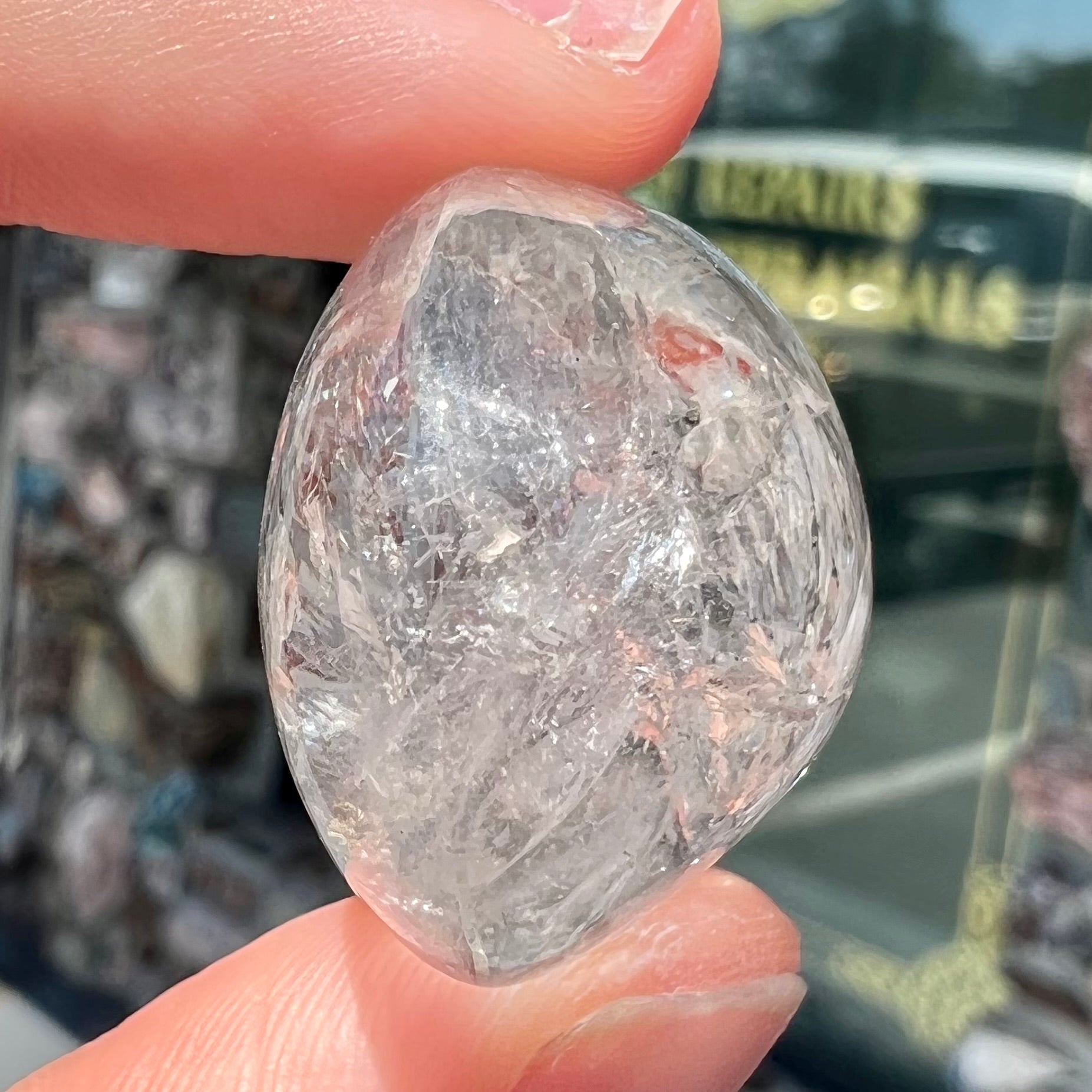 A polished clear quartz with two liquid enhydro inclusions around a solid phantom crystal inclusion.