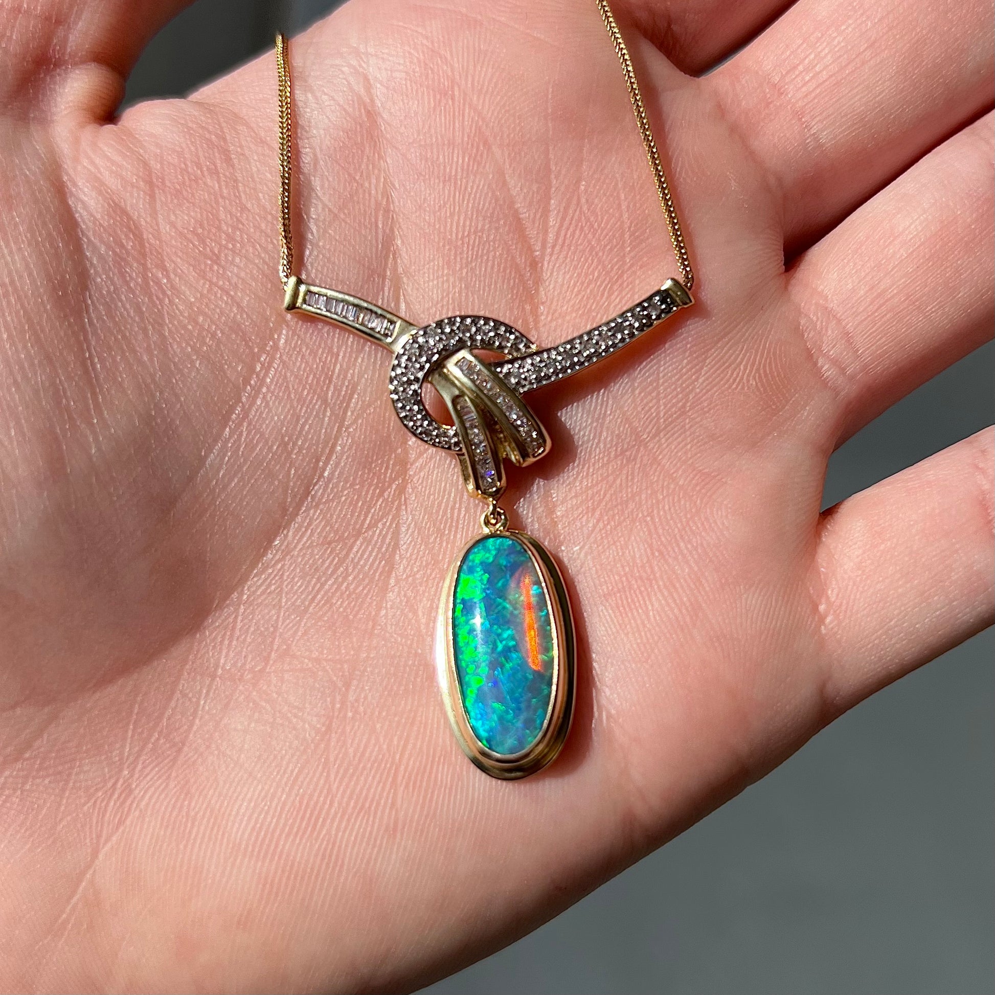 A gold black opal and diamond necklace.  There are round, princess cut, and baguette cut diamonds.