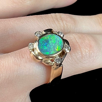 A ladies' yellow gold oval cut natural black opal ring set with five round accent diamonds.