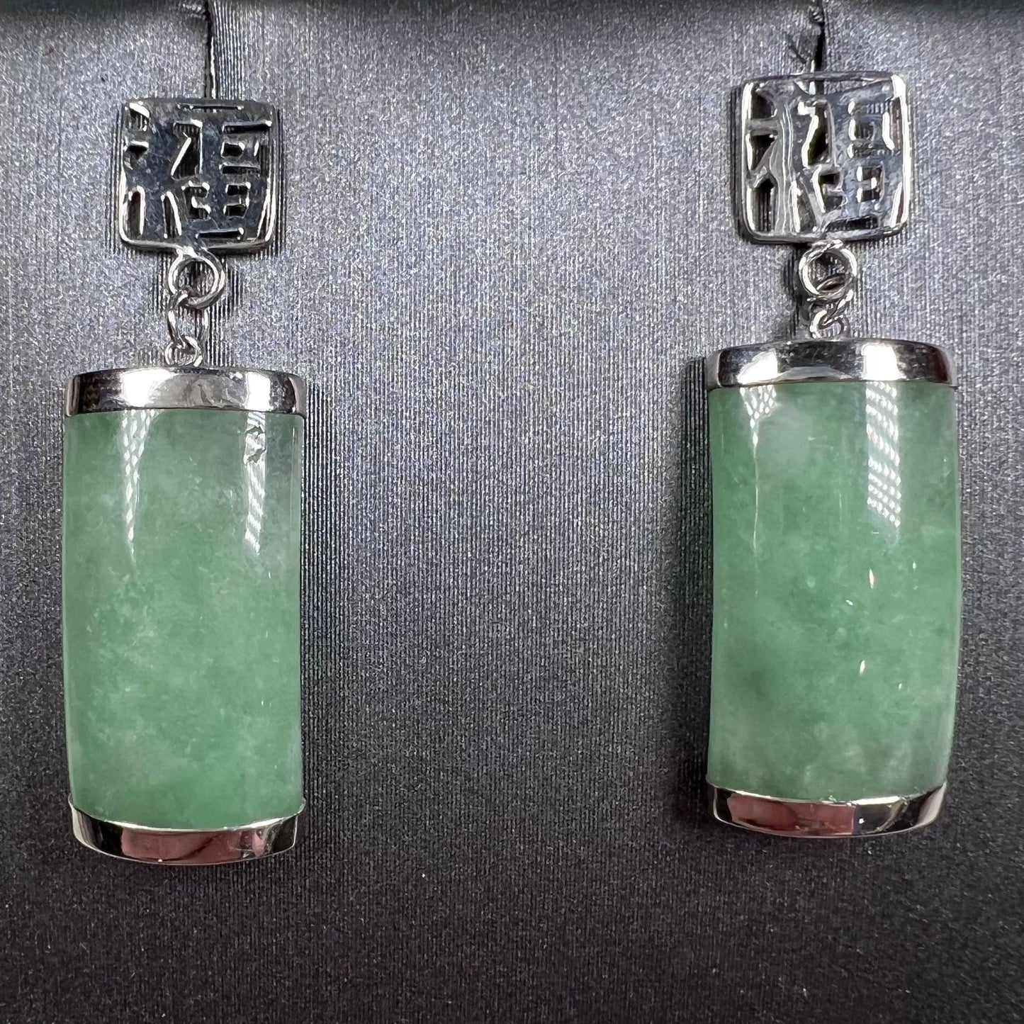 A pair of white gold jadeite dangle earrings with Chinese characters.