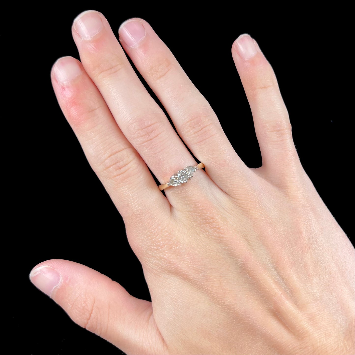 A ladies' three stone diamond ring.  The center diamond is a round brilliant cut, and the two accents are heart shaped diamonds.