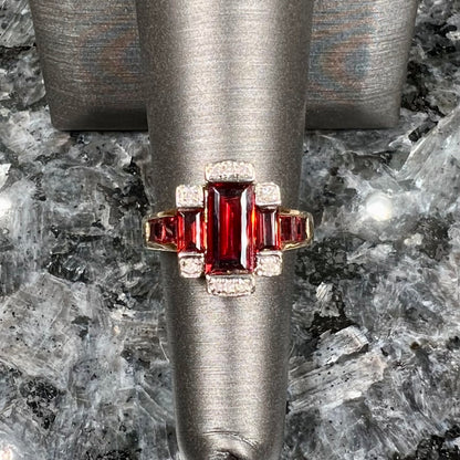 An Art Deco style emerald cut garnet and diamond ring cast in yellow gold.