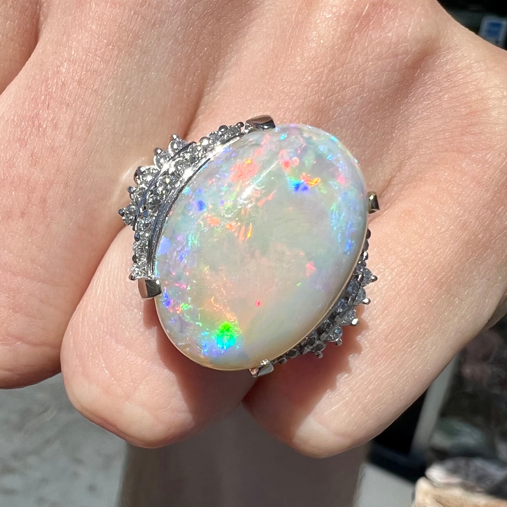 An oval cabochon cut Coober Pedy, Australian opal prong set in a platinum ring with round cut diamonds.