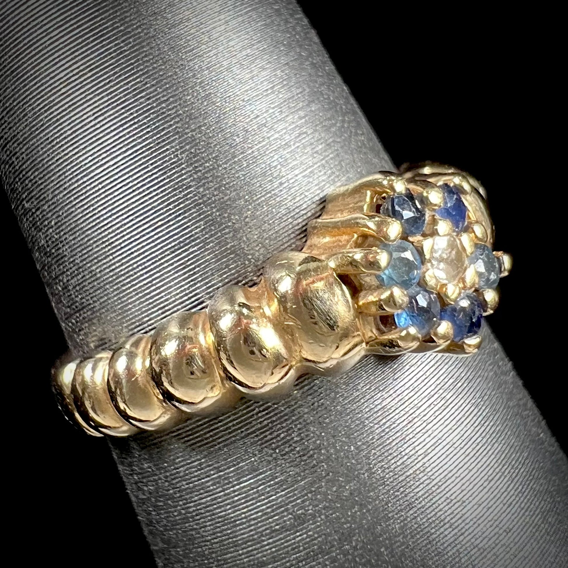 A ladies' yellow gold cluster ring set with round blue sapphires and a round diamond.