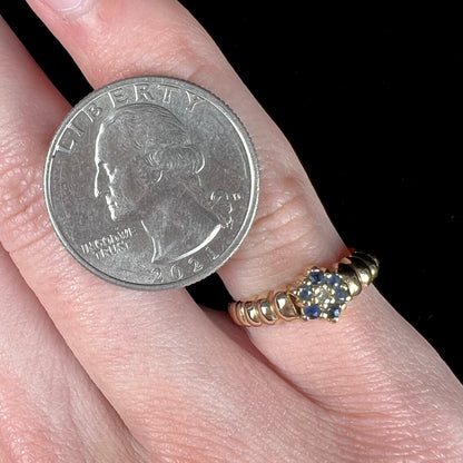 A ladies' yellow gold cluster ring set with round blue sapphires and a round diamond.