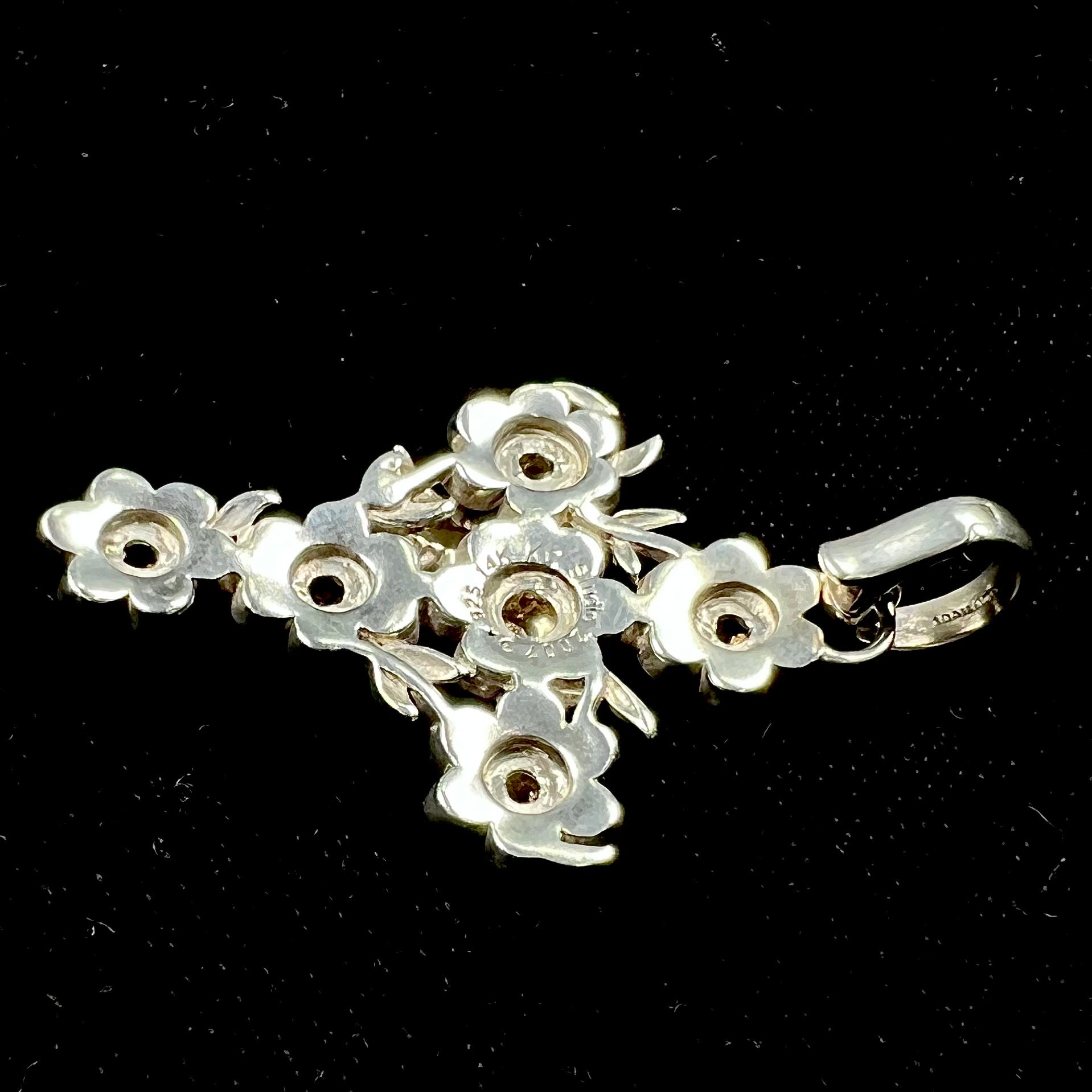 A cross pendant with floral decoration.  The cross is made of six  flowers with sterling silver petals and yellow gold nectar.  A silver bee is on one of the pendants.  The bail opens and closes.