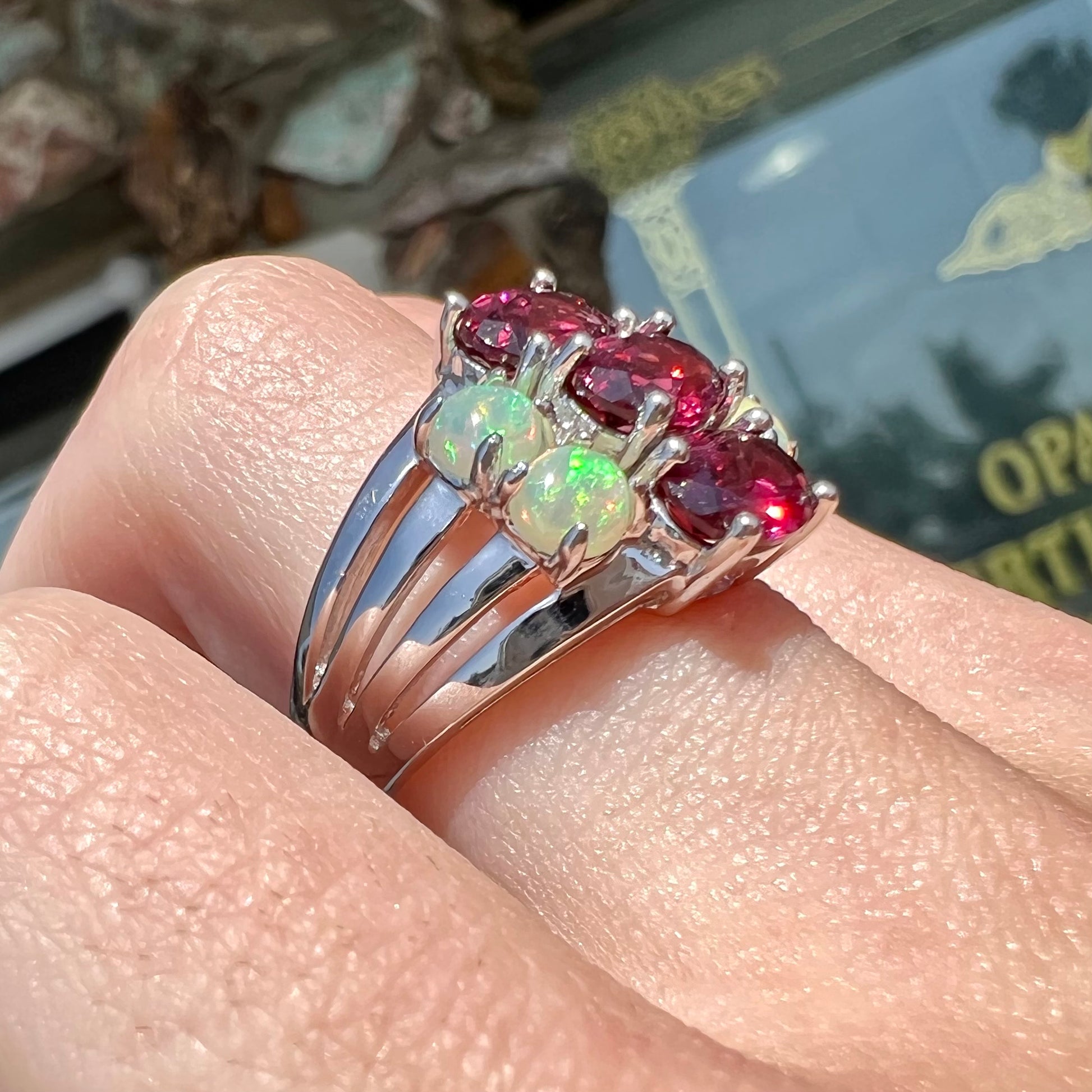 A sterling silver ring set with three oval cut rhodolite garnets and four round cabochon cut Ethiopian opals.