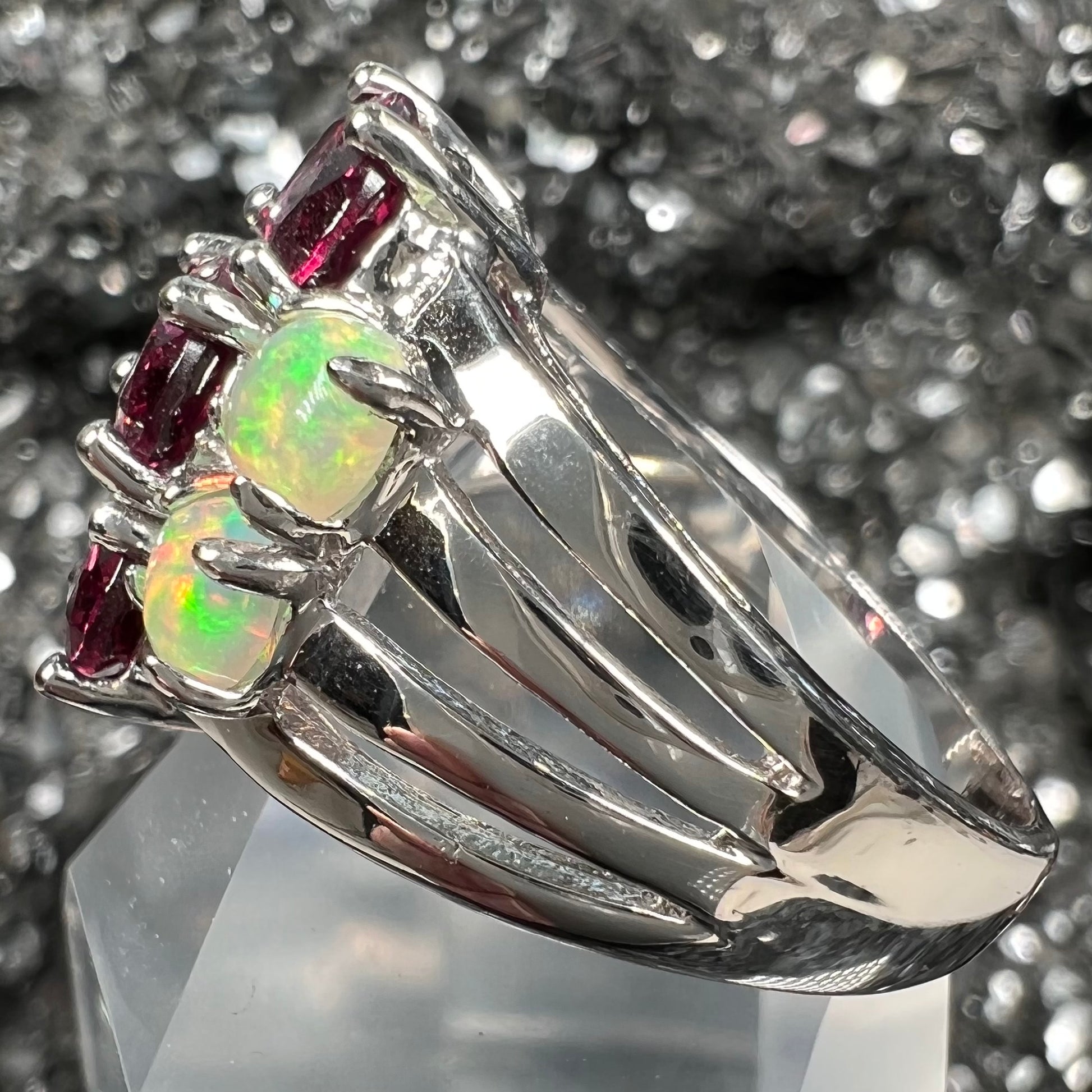 A sterling silver ring set with three oval cut rhodolite garnets and four round cabochon cut Ethiopian opals.
