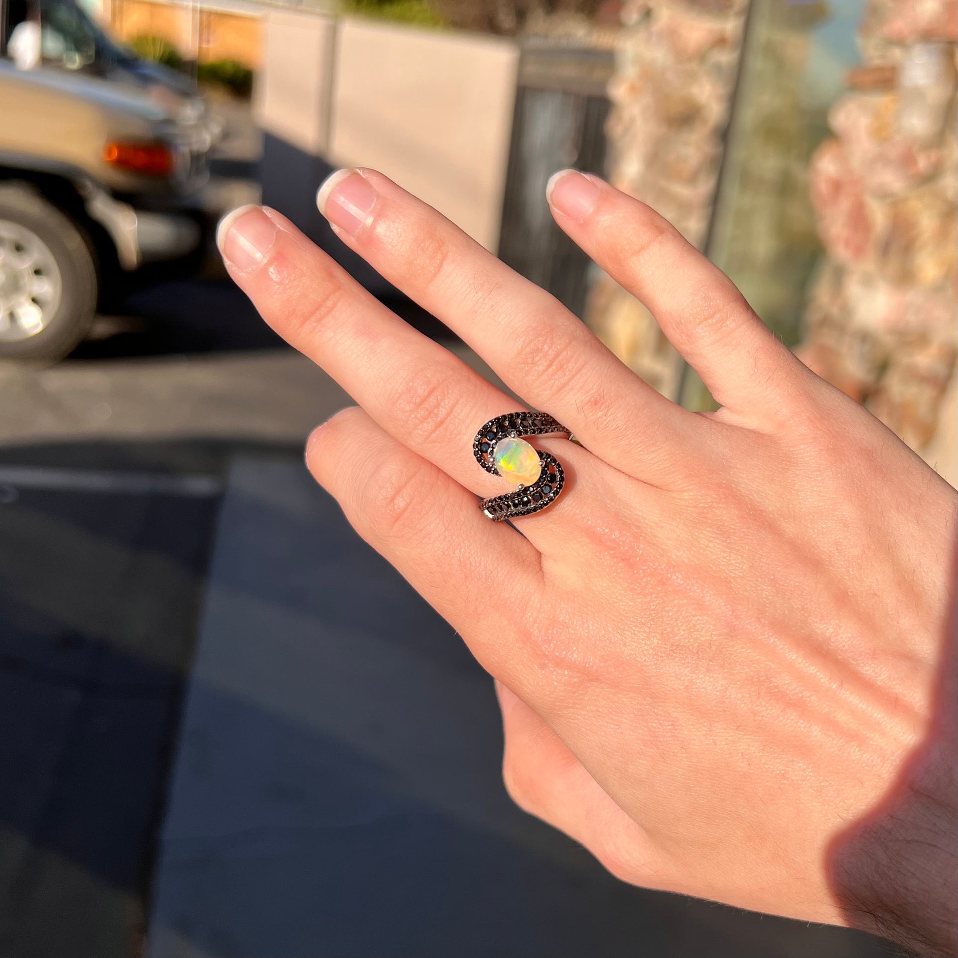A sterling silver ring set with round black spinel stones and an oval cut, faceted Ethiopian opal.