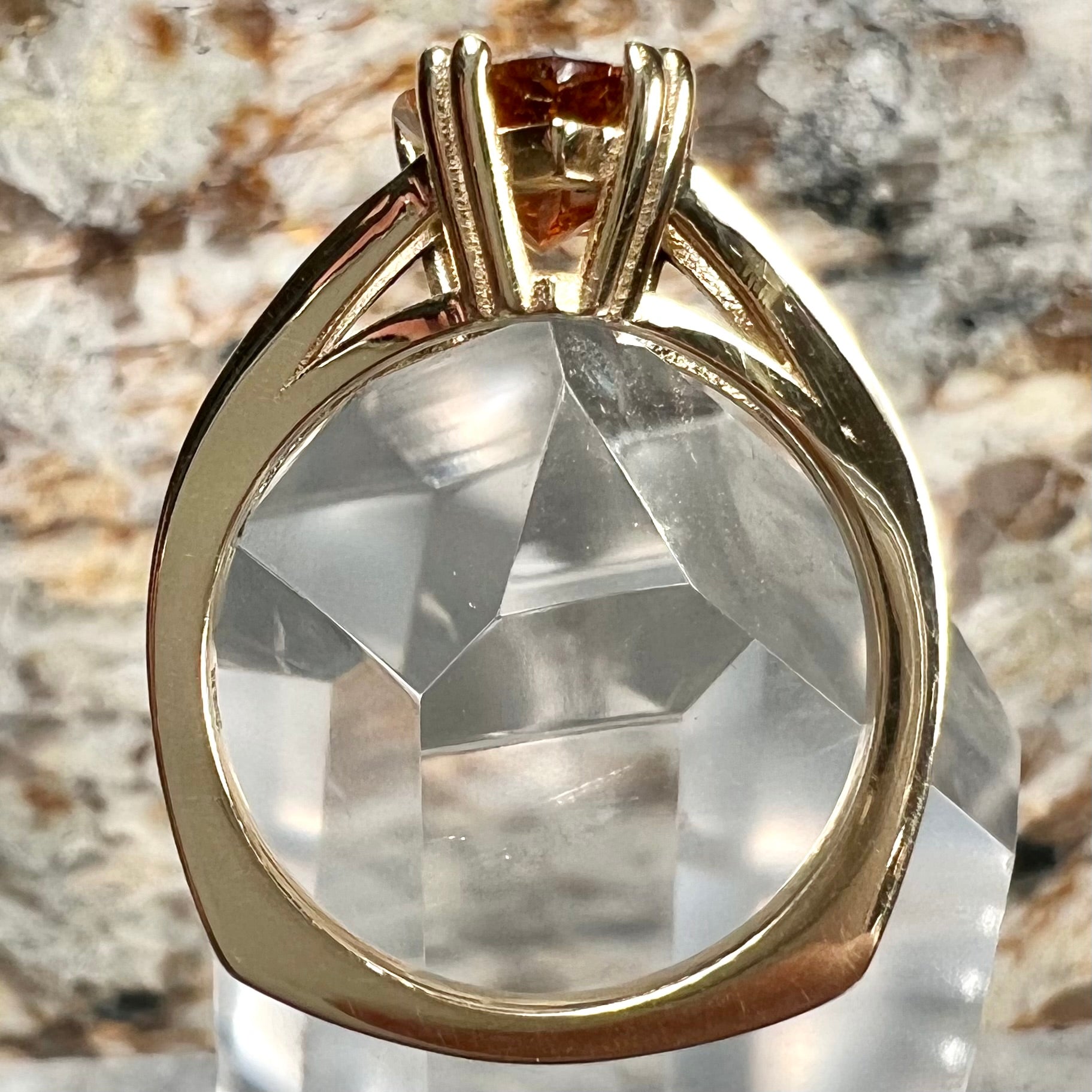 A gold split Euro shank solitaire ring set with an orange pear shape hessonite garnet stone.