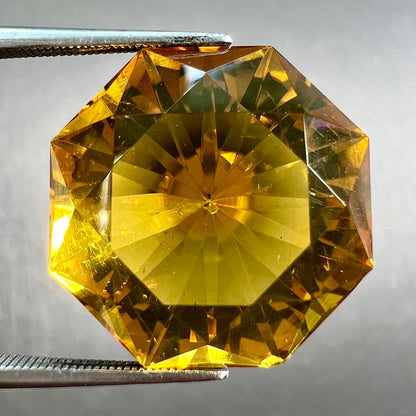 A loose, faceted octagonal cut golden amber stone.  There are no bug inclusions visible.