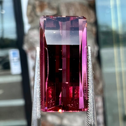 A loose, fantasy cut reddish colored tourmaline.  The cut reflects light in a way that resembles digital pixels on a screen.