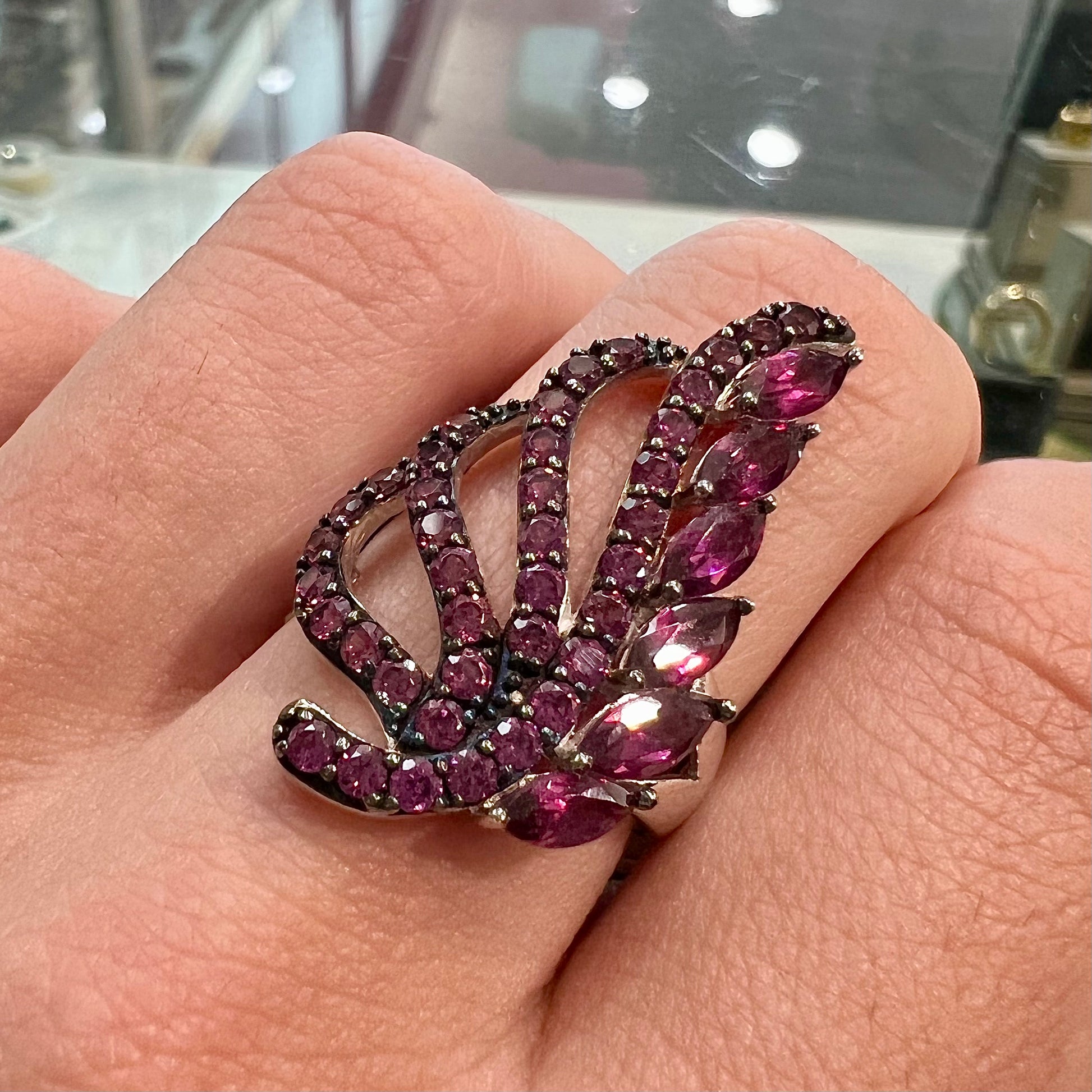 A sterling silver, feather shaped ring set with round and marquise cut rhodolite garnet stones.