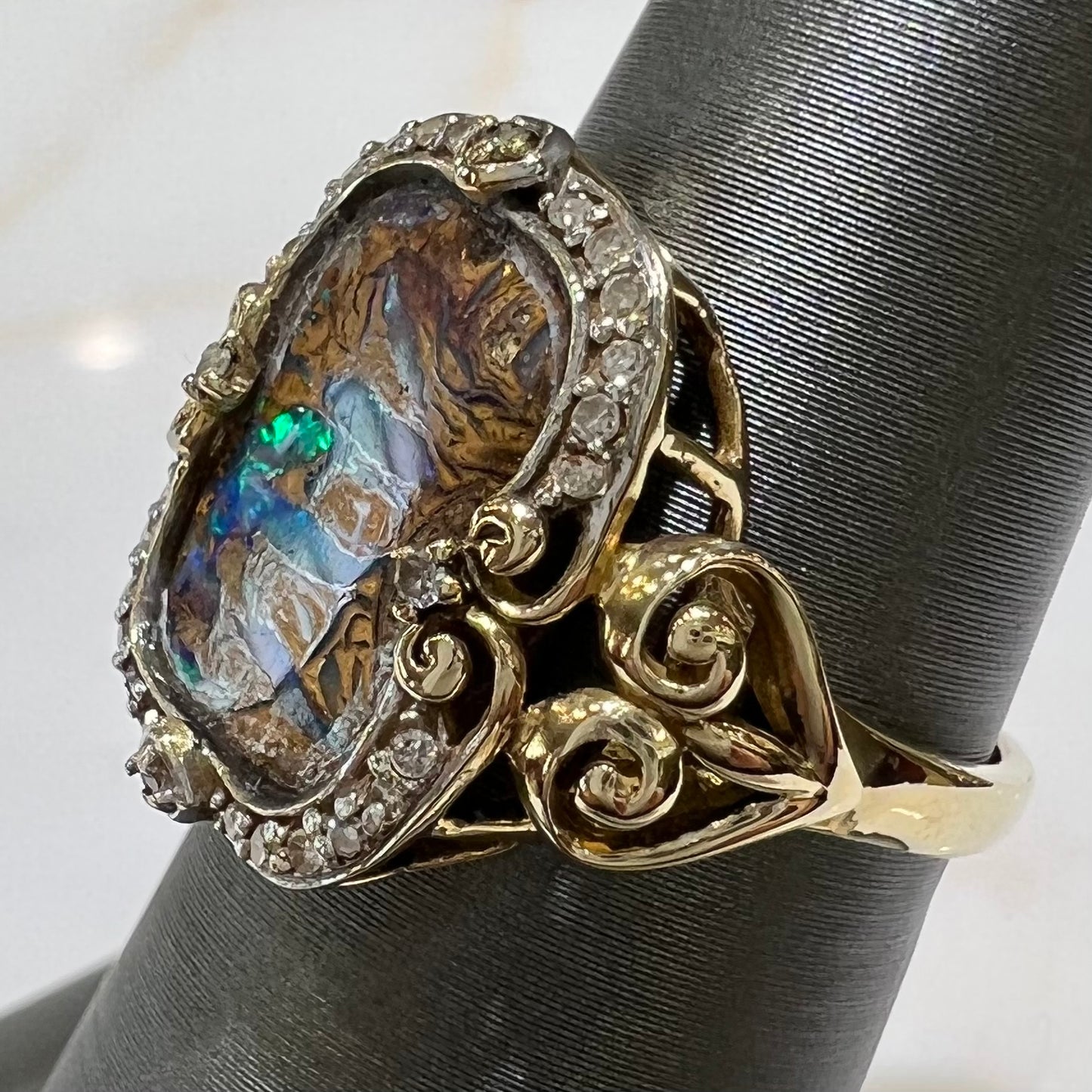 Striped Koroit boulder opal set in a filigree 14k yellow gold setting with diamonds.  The filigree has a heart pattern.