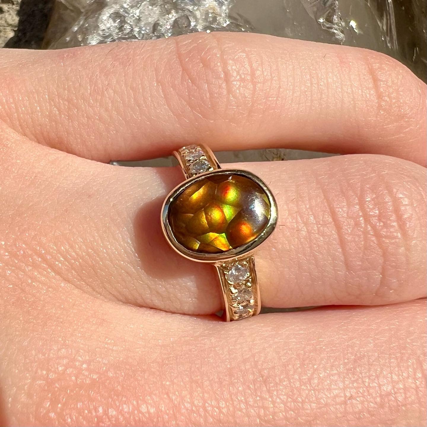A ladies' oval cabochon cut fire agate and diamond engagement ring cast in yellow gold.