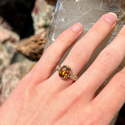 A ladies' oval cabochon cut fire agate and diamond engagement ring cast in yellow gold.