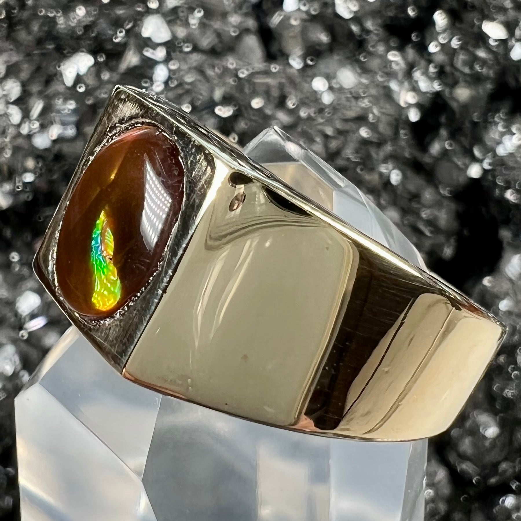 A men's yellow gold flush set fire agate solitaire ring.  The fire agate displays flashes of green, orange, and yellow.