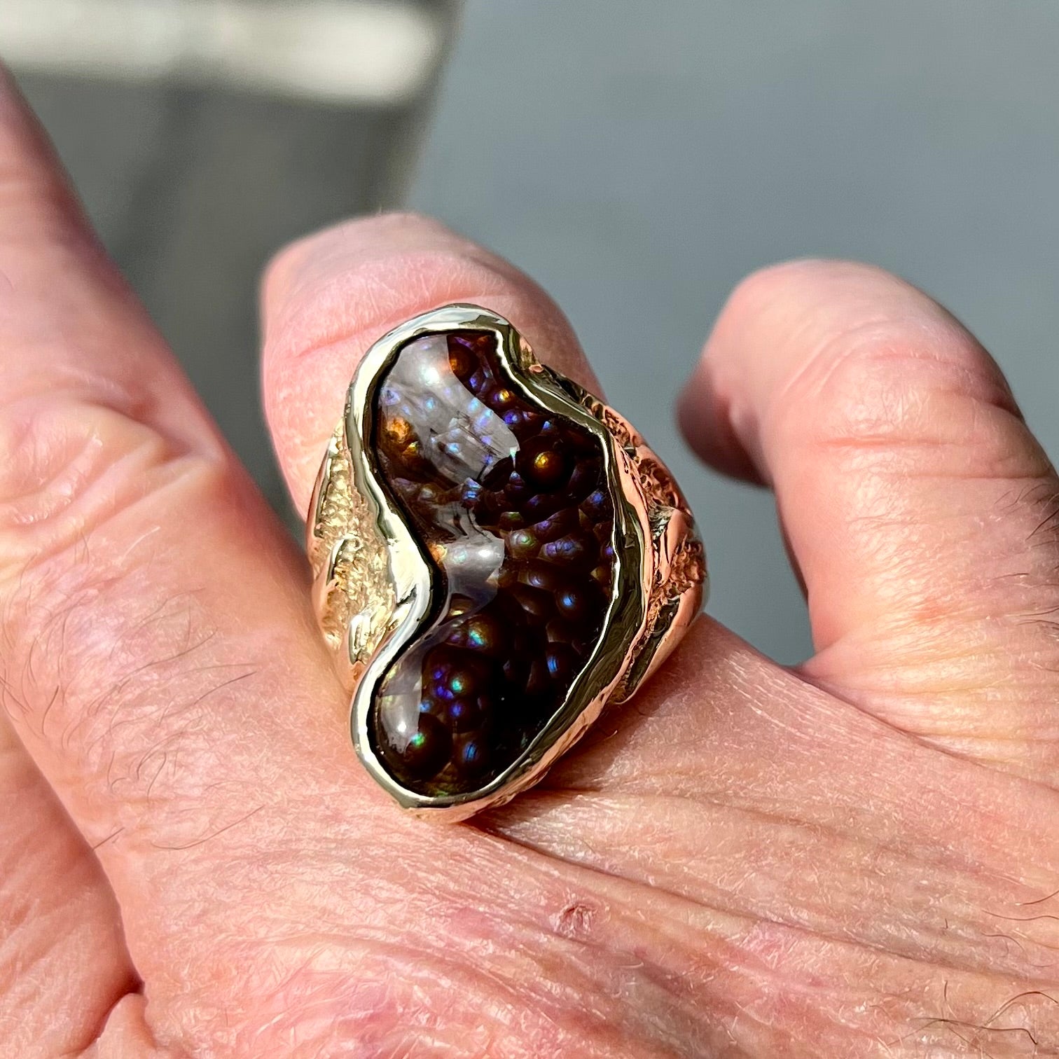 A men's Deer Creek fire agate solitaire ring cast in yellow gold.  The stone is predominantly purple.