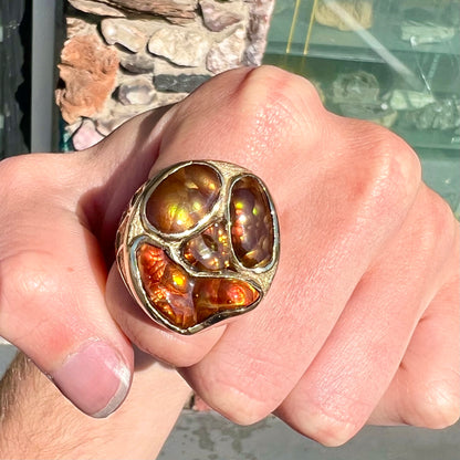 A yellow gold men's thug ring set with four fire agate stones resembling a spooky face.