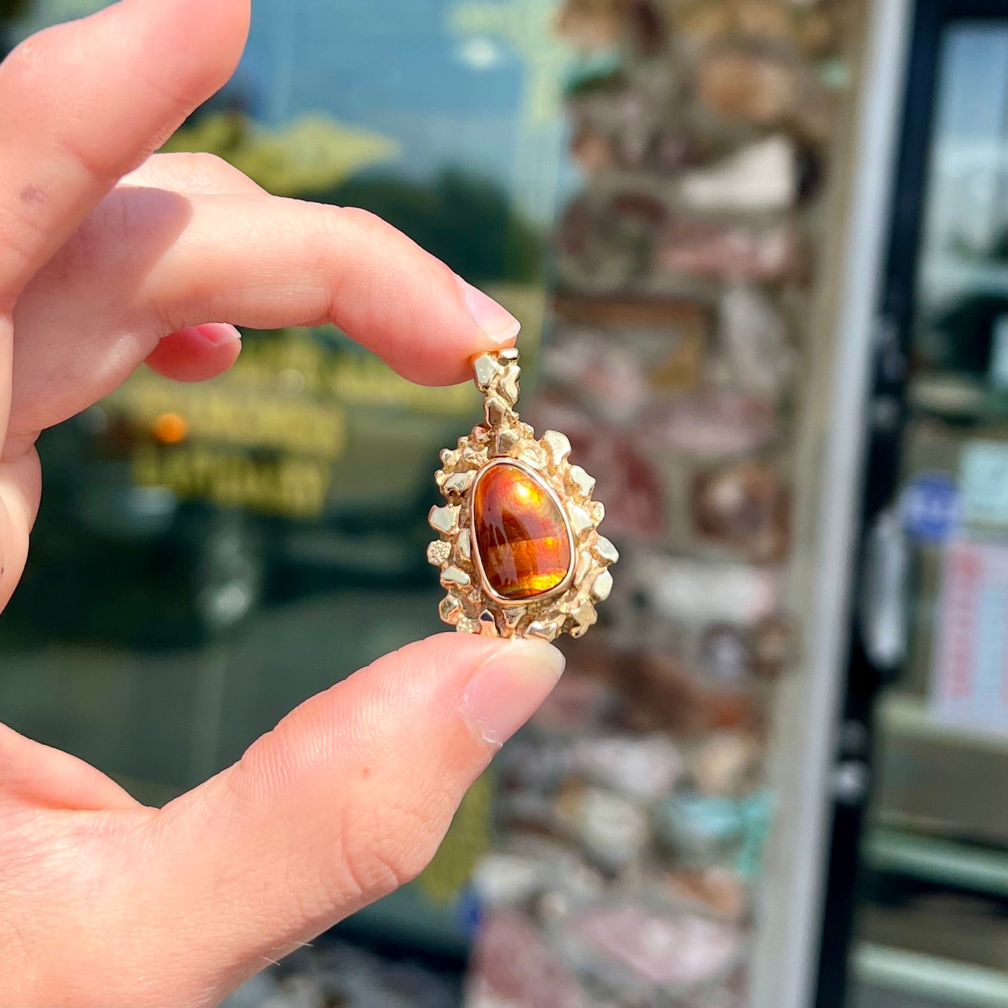 A gold nugget style pendant set with a freeform cabochon cut fire agate stone.